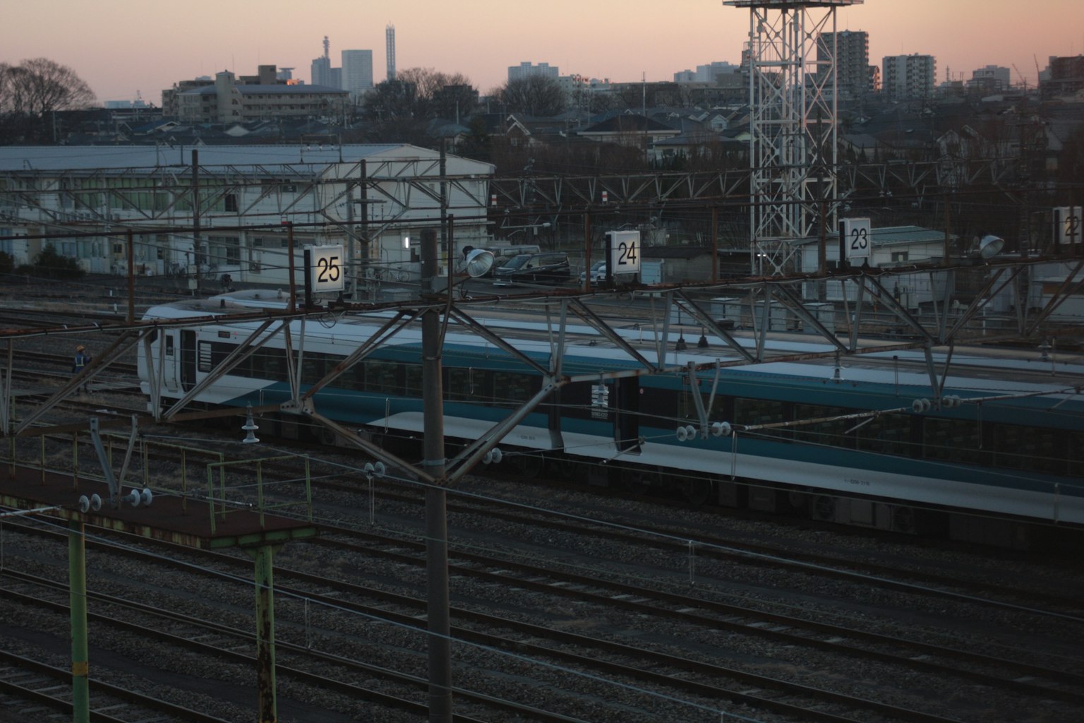 Train parked on railway tracks during dusk with surrounding buildings