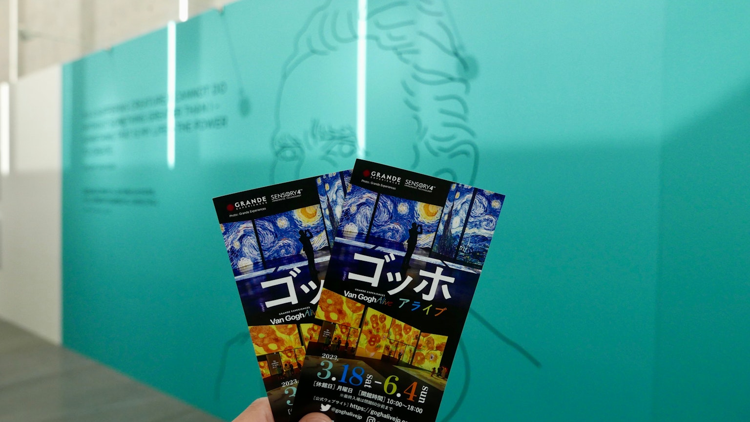 Two tickets in front of a blue wall featuring a line drawing of a person