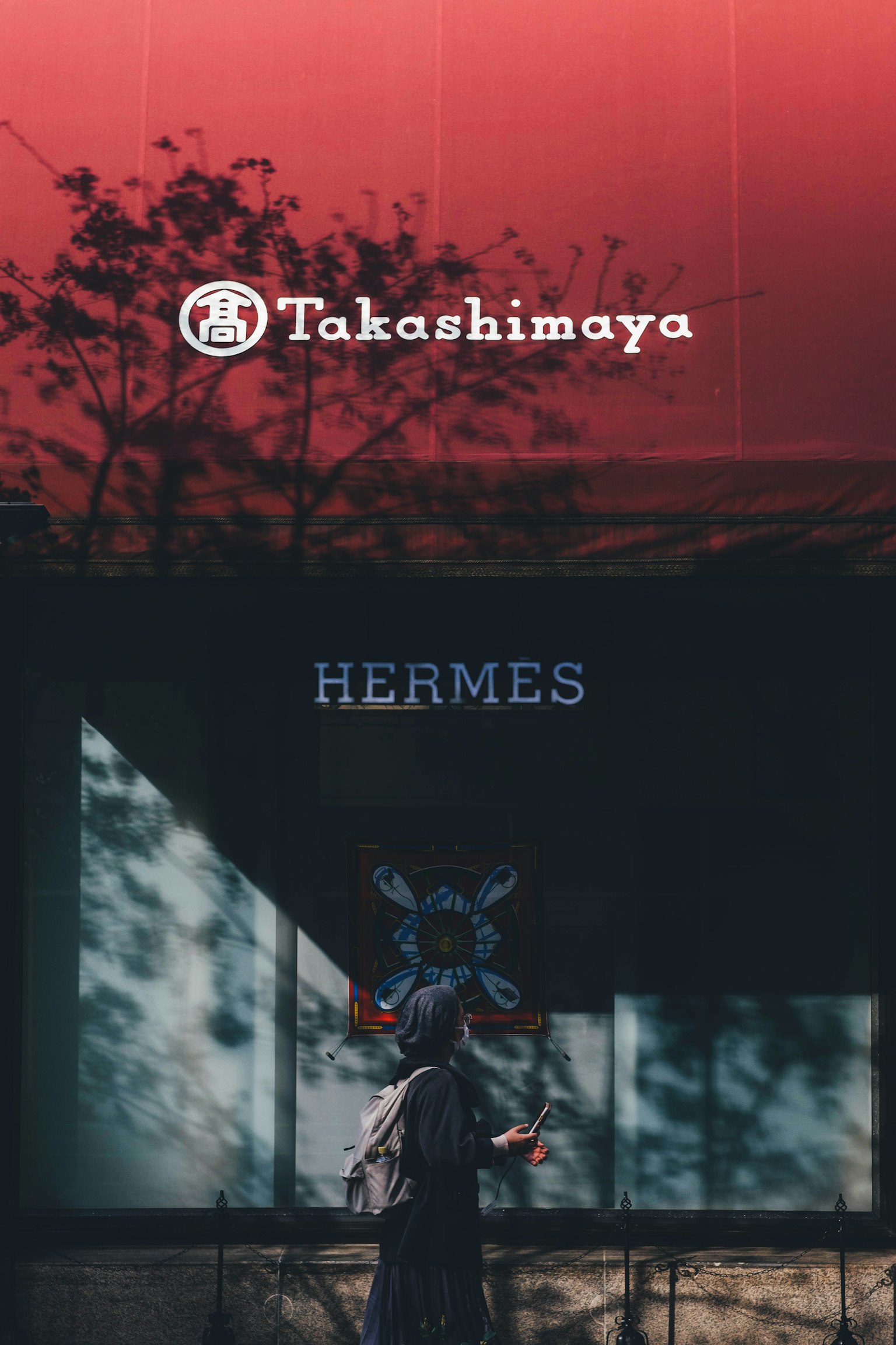 Takashimaya-Logo und Hermes-Schild in einem städtischen Umfeld