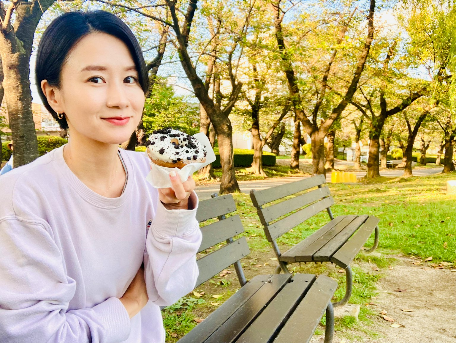 一位女性在公园里手持冰淇淋，周围有绿草和长椅