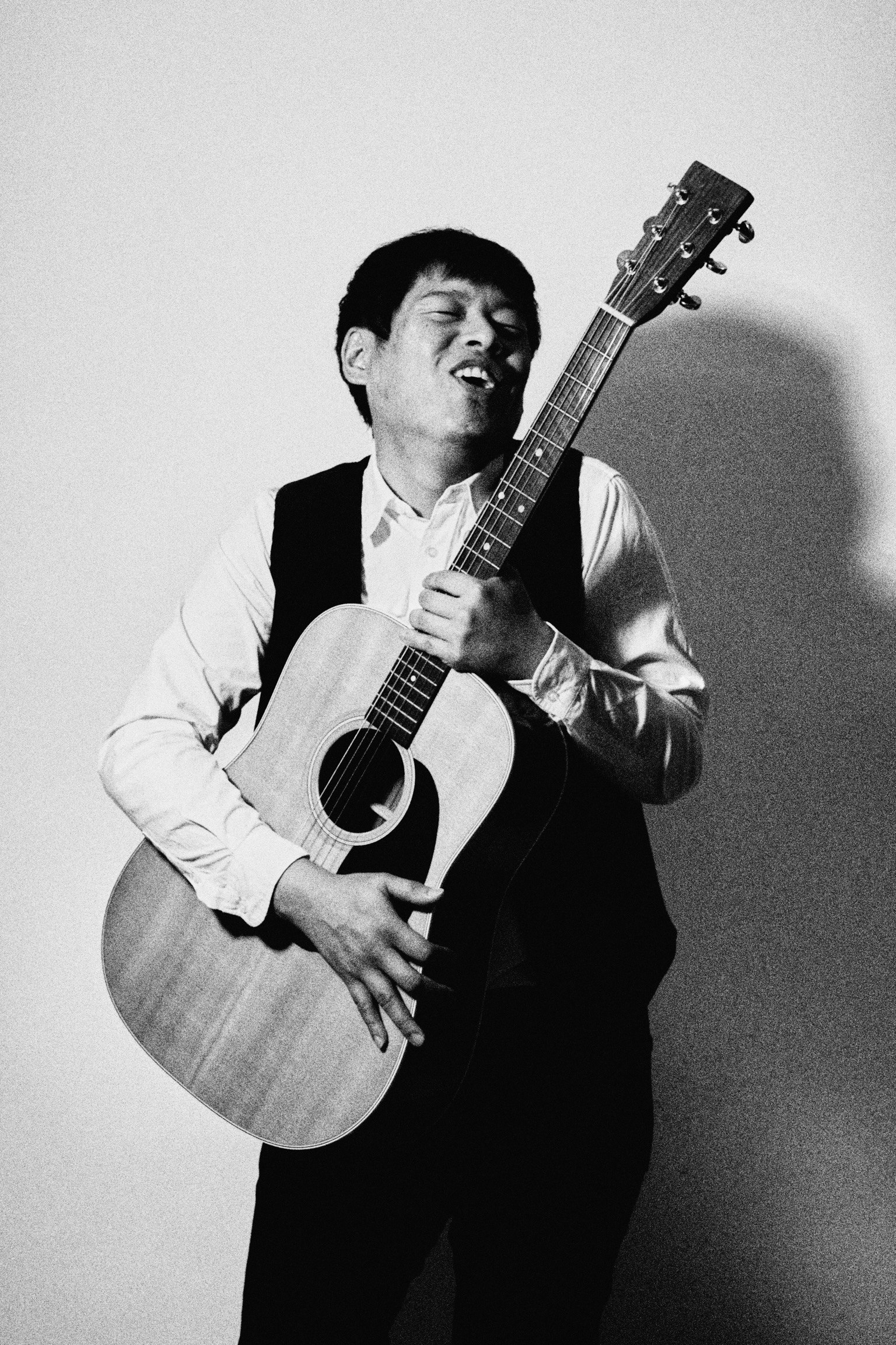 Foto hitam putih seorang pria bermain gitar dengan penuh semangat