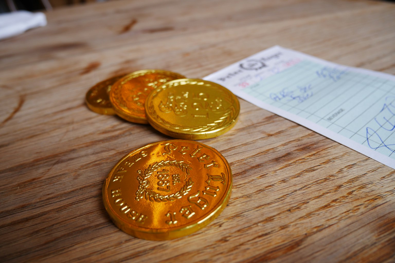 Goldmünzen und ein Notizblatt auf einem Holztisch