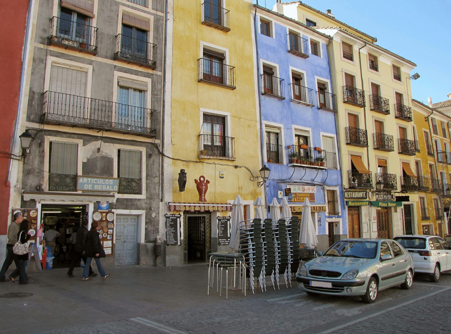 Edificios coloridos que bordean una plaza con personas caminando