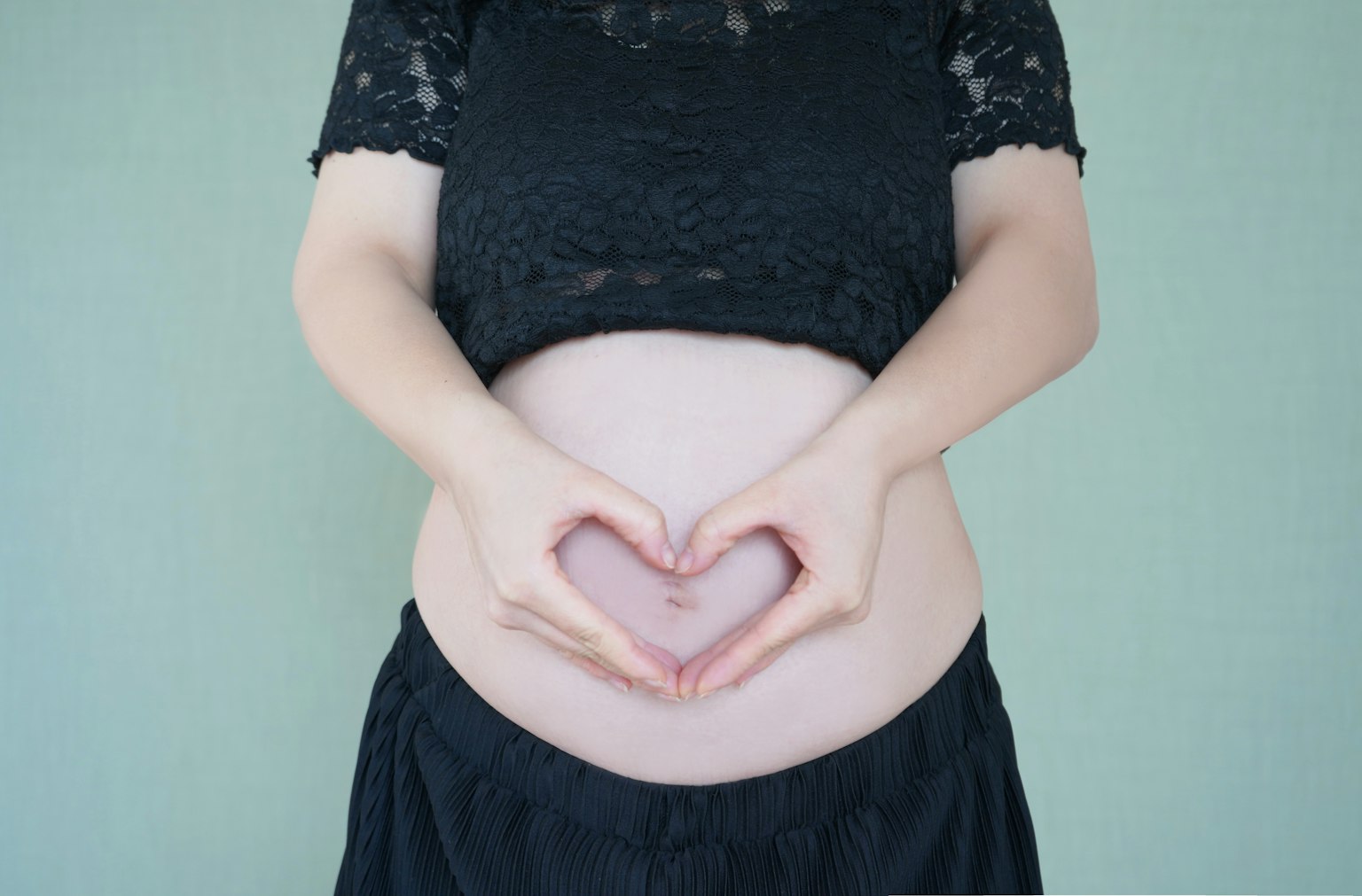Pregnant woman forming a heart shape with hands on her belly