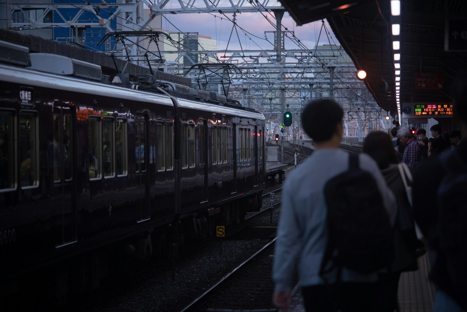 People waiting on a train platform during twilight