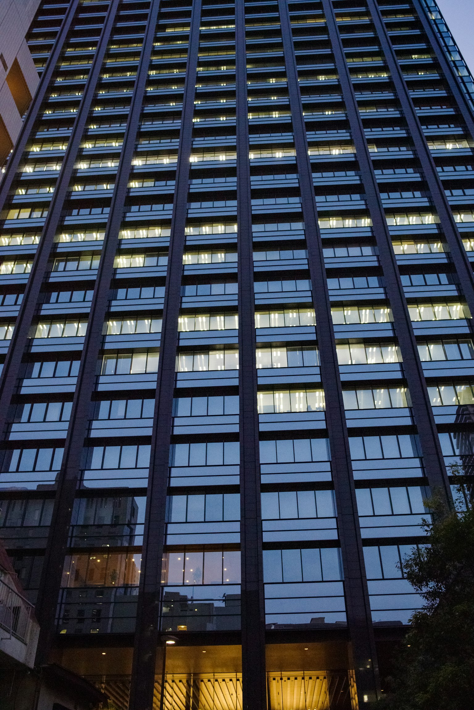 Hochhaus mit beleuchteten Fenstern in der Dämmerung