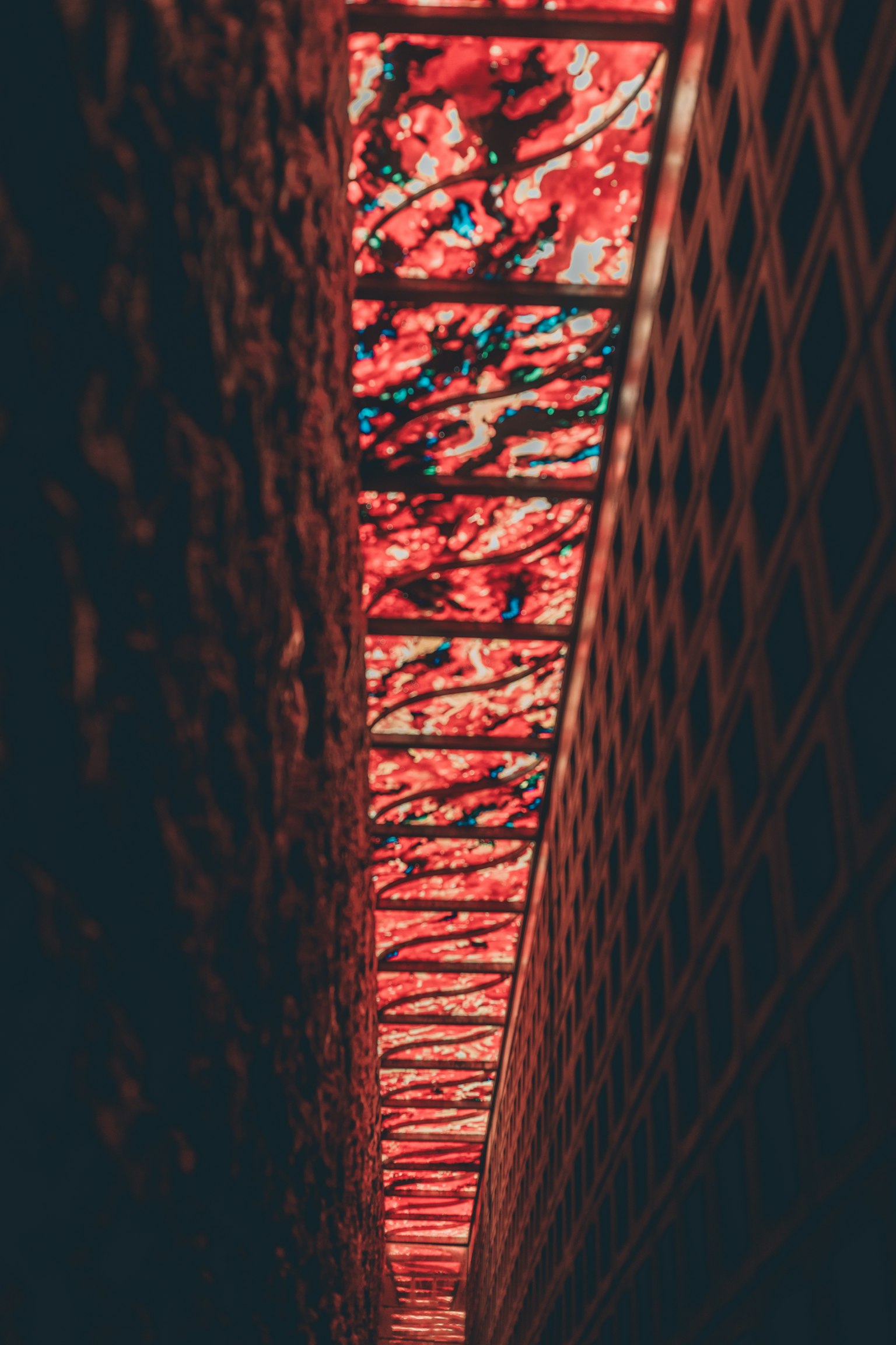 Passage étroit illuminé par une lumière rouge avec des panneaux en verre décorés