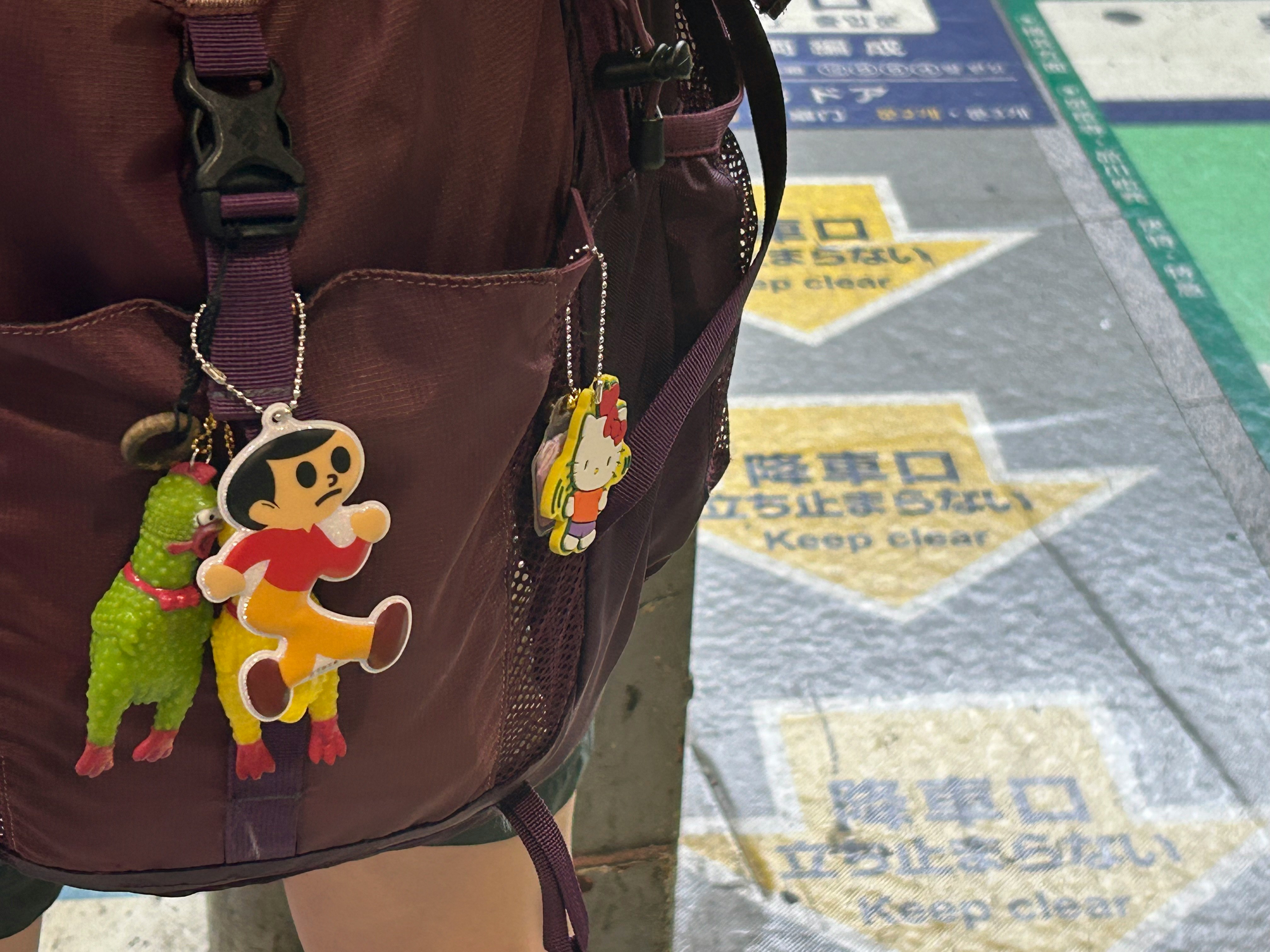 キャラクターのキーホルダー付きのバッグと床の注意表示