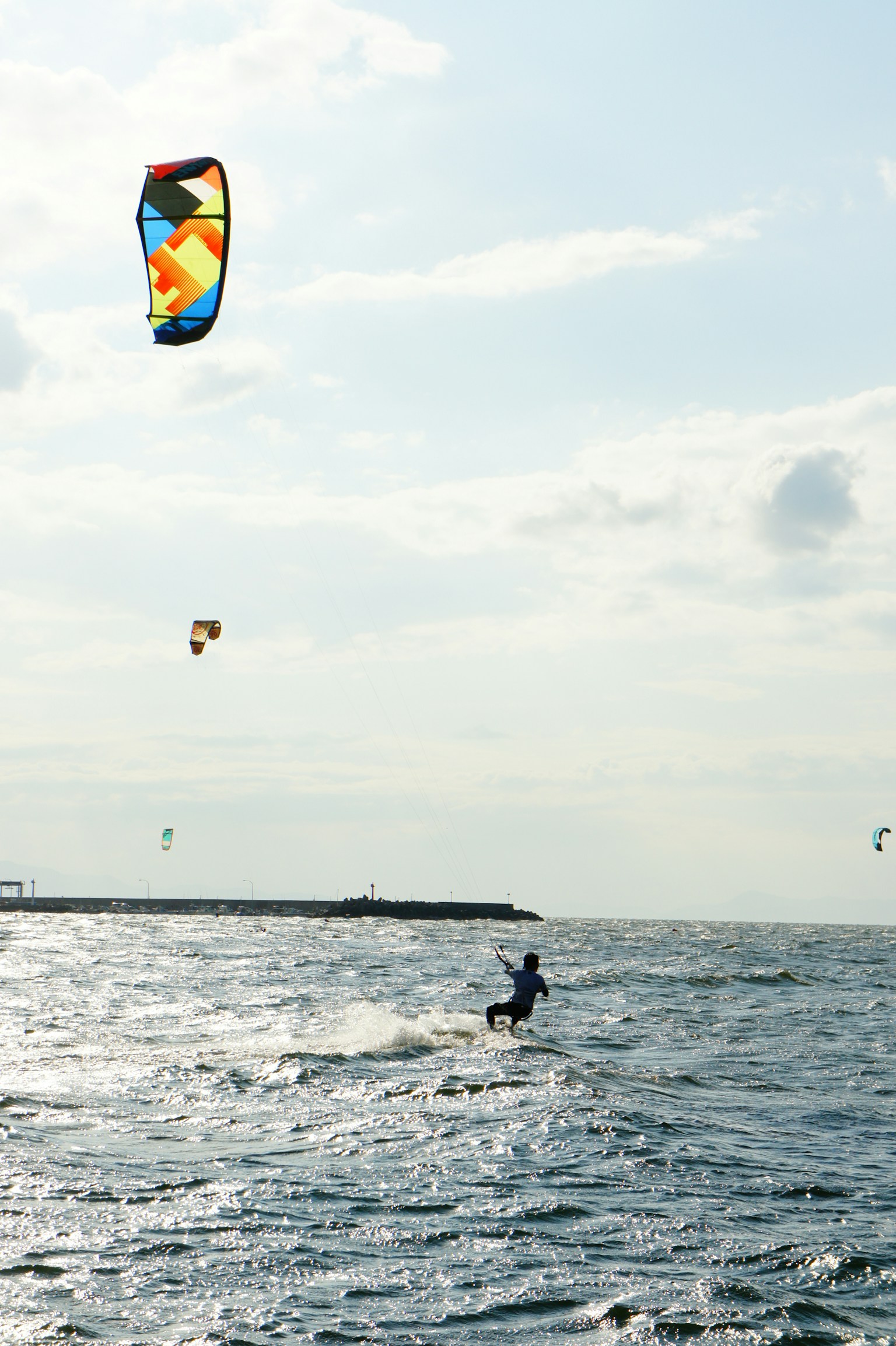 A person kitesurfing with a colorful kite in a serene ocean setting