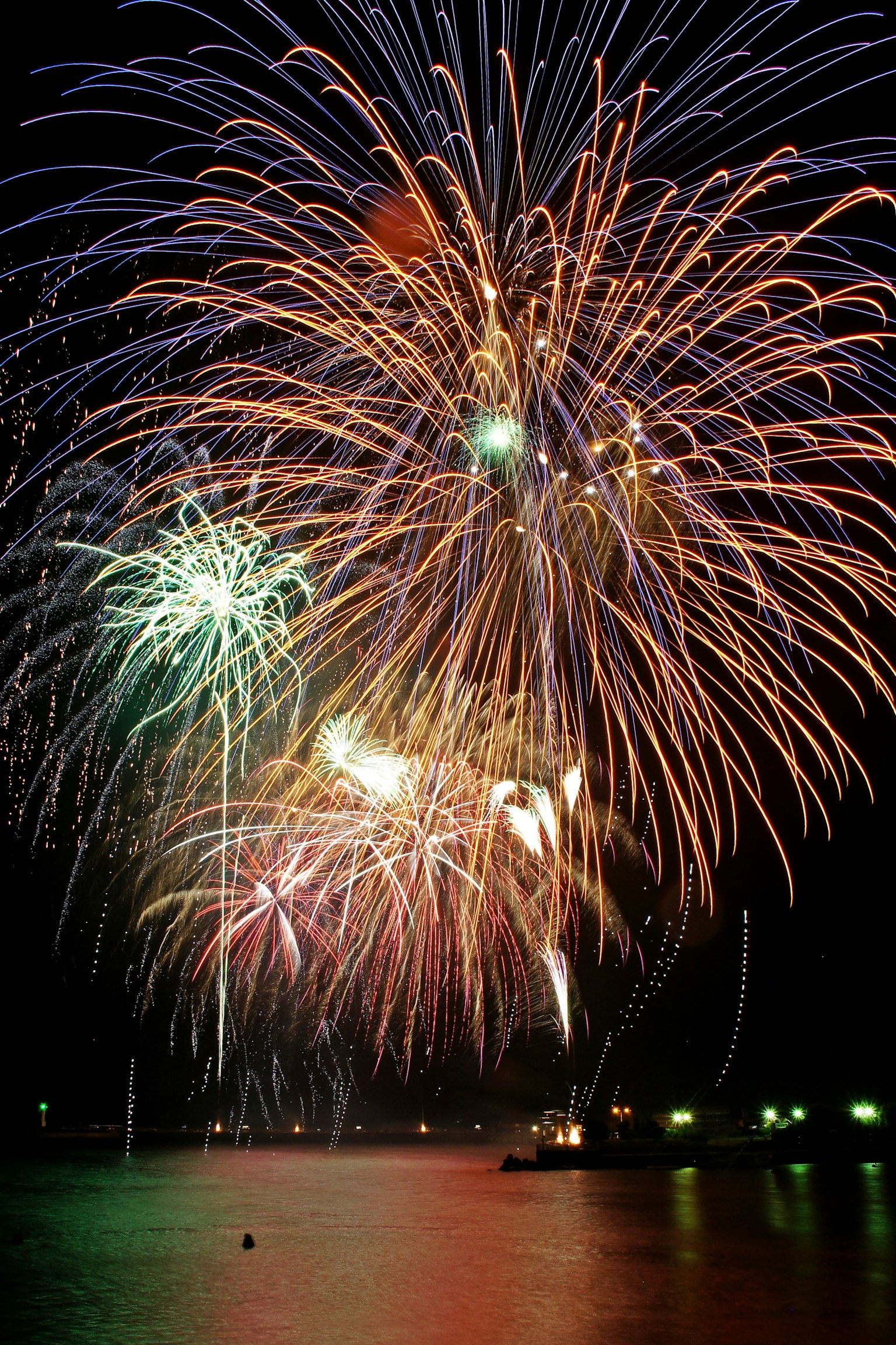 Colorful fireworks bursting in the night sky over water