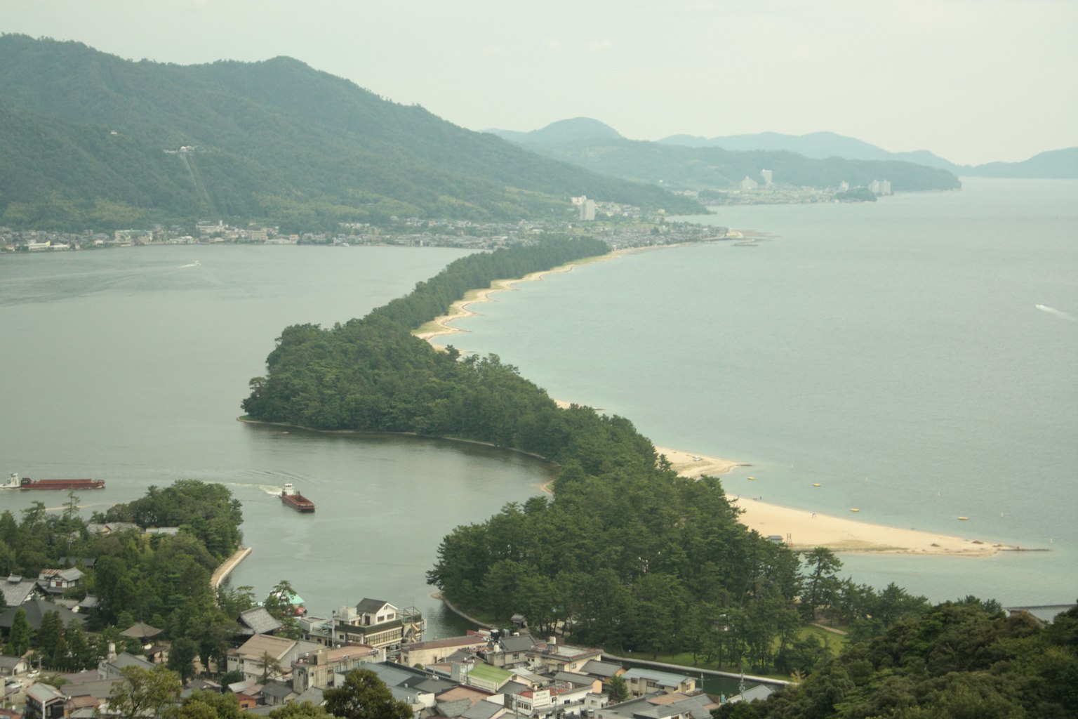 Malerscher Blick auf eine grüne Insel entlang der Küste mit Bergen im Hintergrund