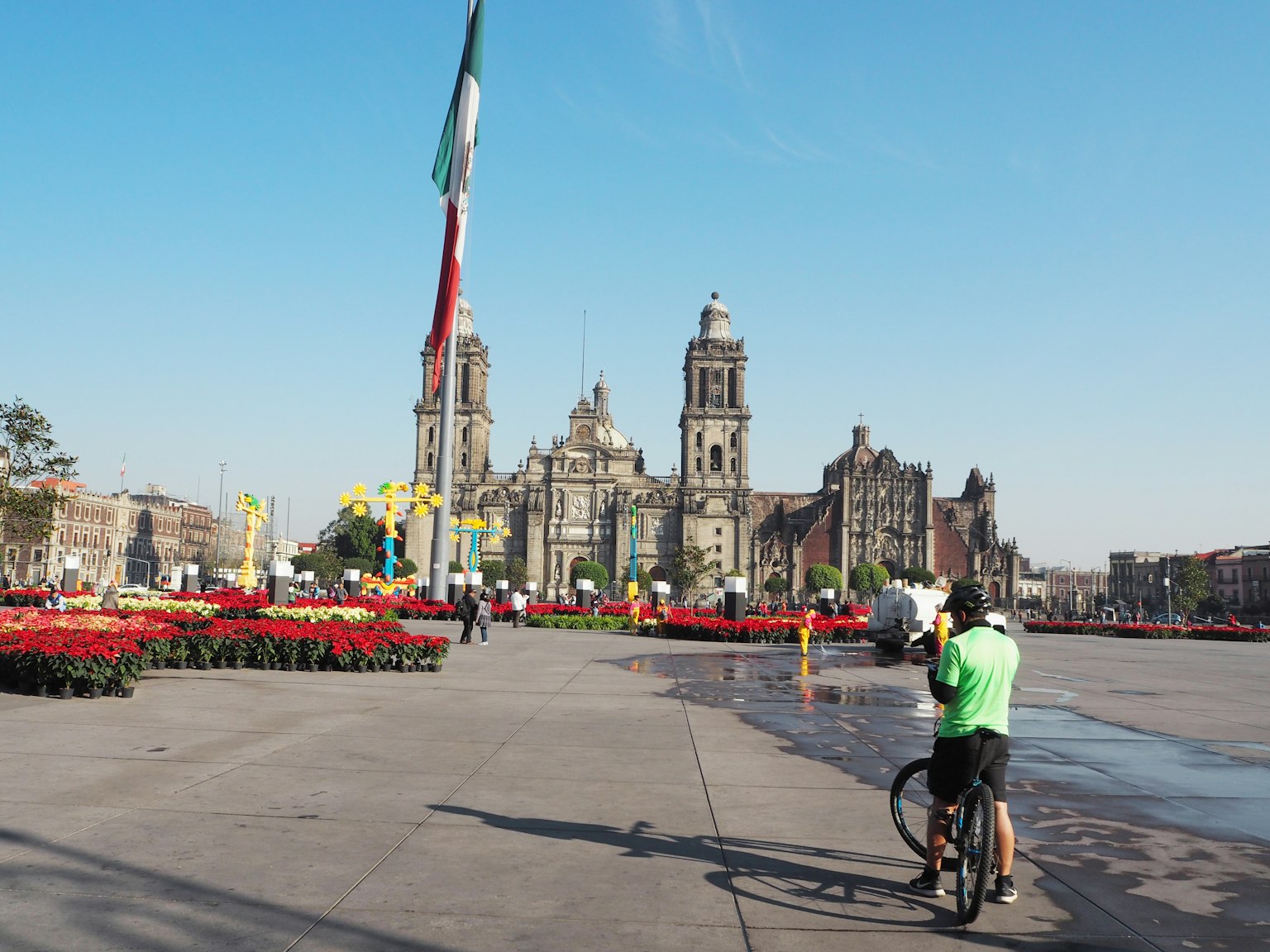 Một người đi xe đạp ở Zocalo của Thành phố Mexico với các tòa nhà lịch sử và hoa tươi sáng