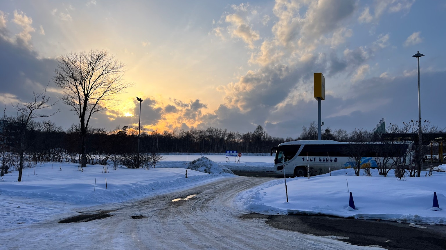 Paisaje nevado con un cielo al atardecer y un autobús estacionado