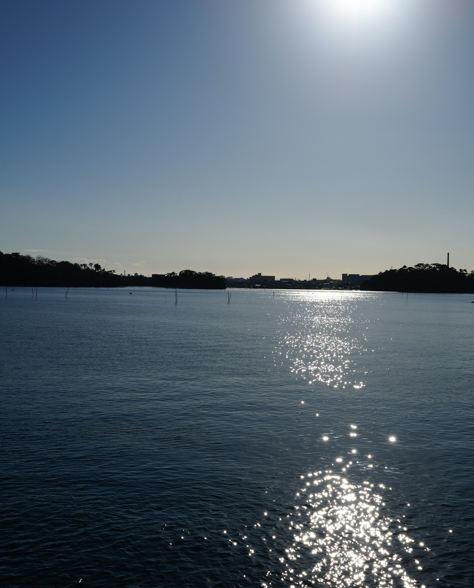 Ruhiges Wasser, das Sonnenlicht mit einer ruhigen Landschaft reflektiert