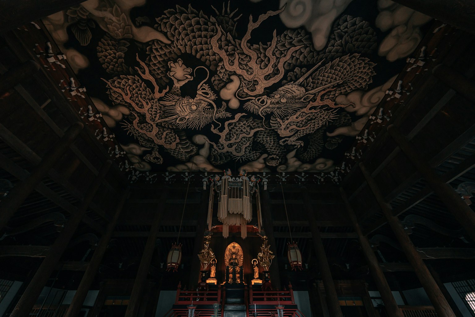 Interno di un tempio con opere d'arte intricate sul soffitto e statue di Buddha sedute