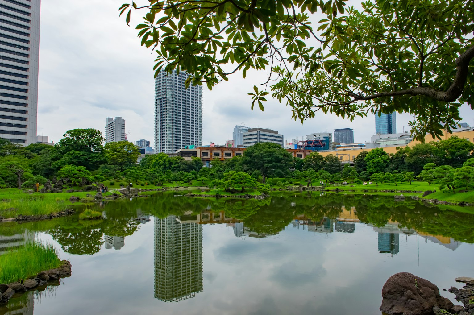 ทิวทัศน์สวนสาธารณะในเมืองพร้อมบ่อน้ำสะท้อนตึกระฟ้า