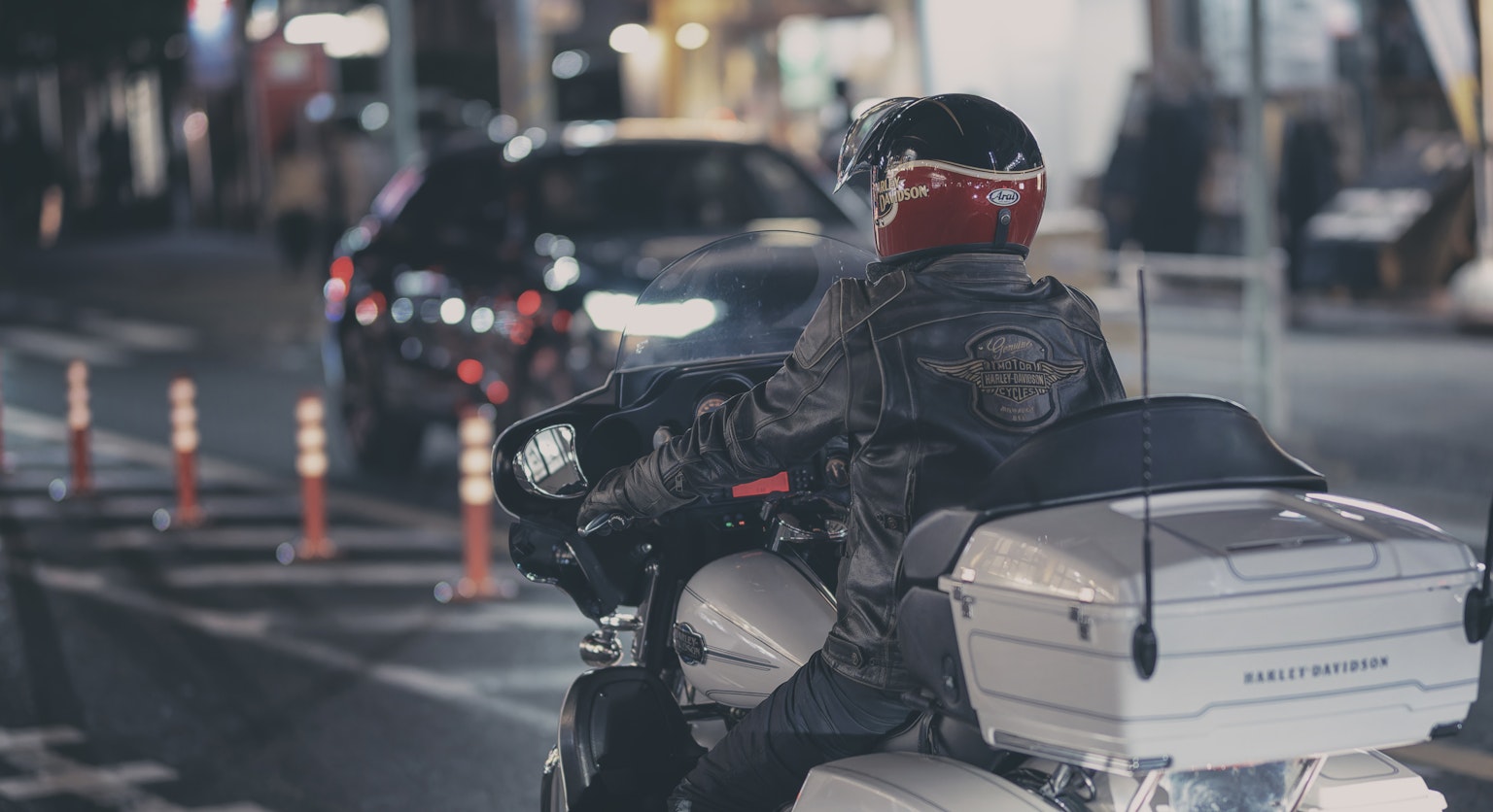 Motociclista su una moto di notte con casco rosso e giacca