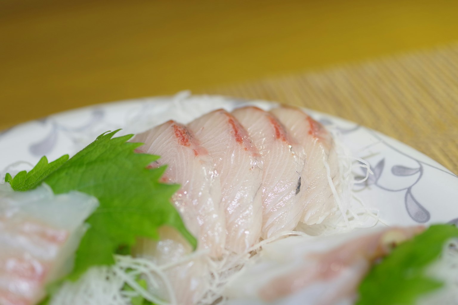 新鲜的生鱼片搭配紫苏叶放在盘子上