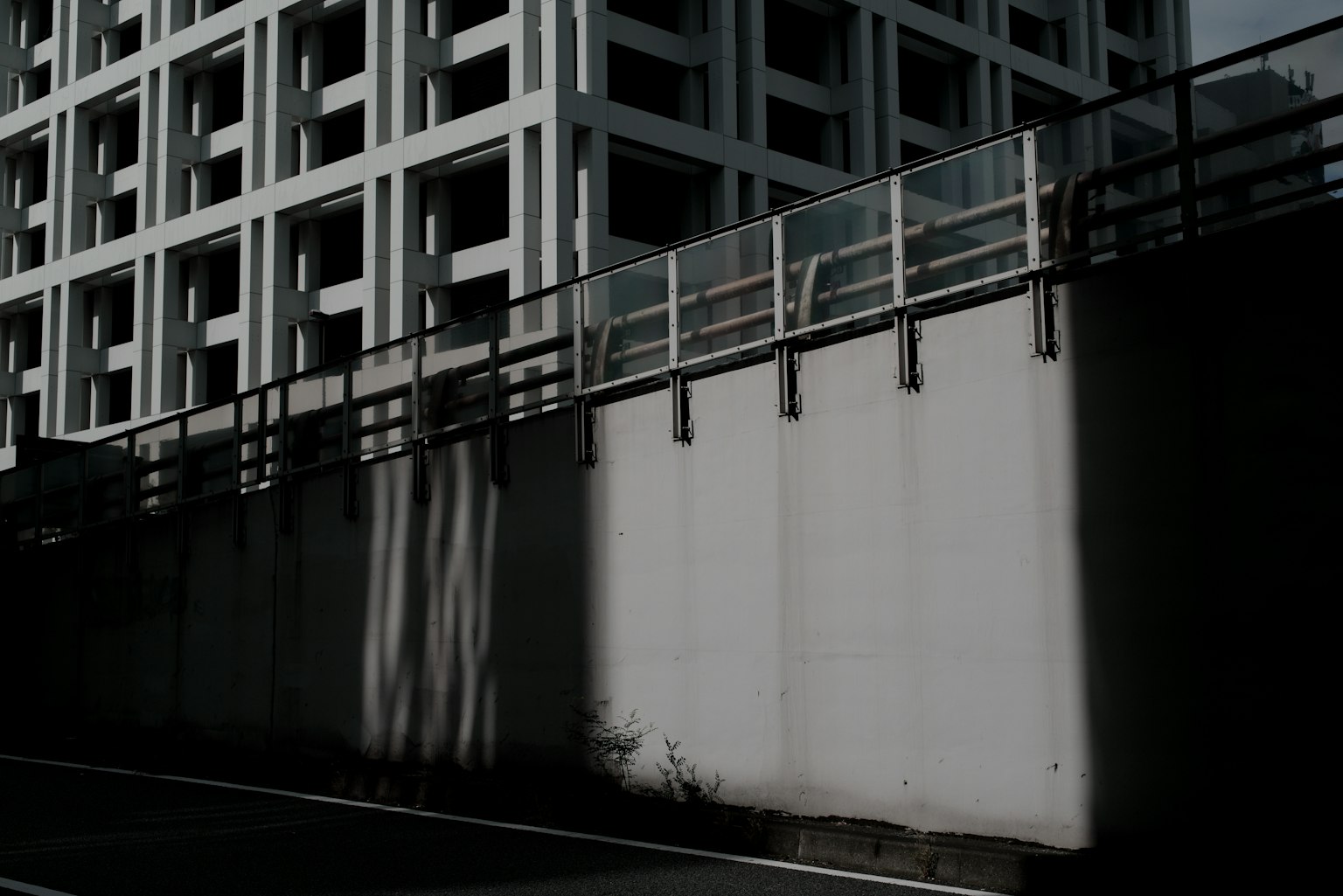 Photo d'un mur en béton et d'une clôture avec des ombres d'un immeuble de grande hauteur