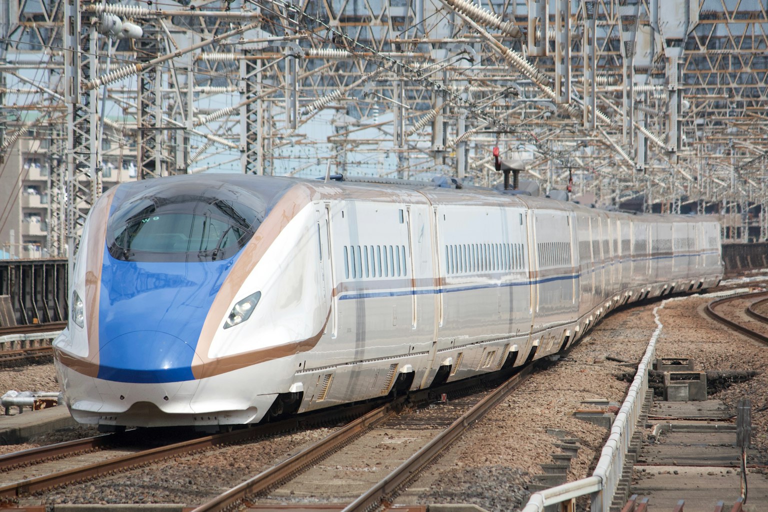 Shinkansen với thiết kế màu xanh và trắng di chuyển quanh khúc cua đường ray