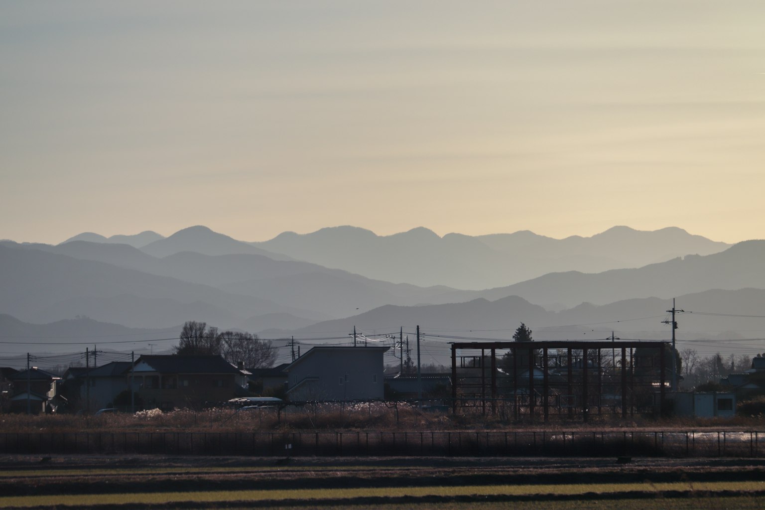 Eine ruhige Landschaft mit Bergen im Hintergrund und ländlichen Gebäuden im Vordergrund