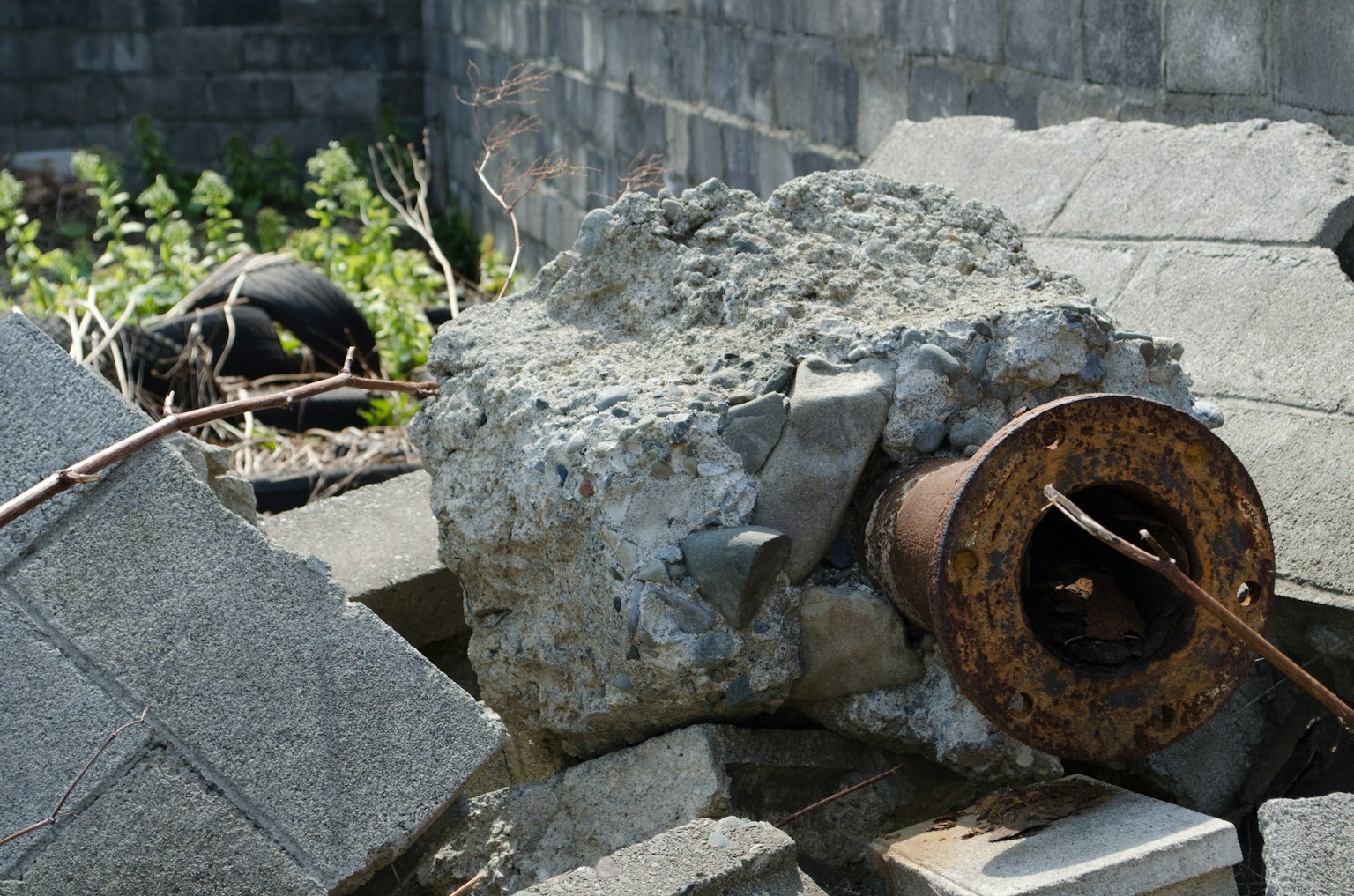 Concrete block and rusty metal cylinder among debris in a ruin