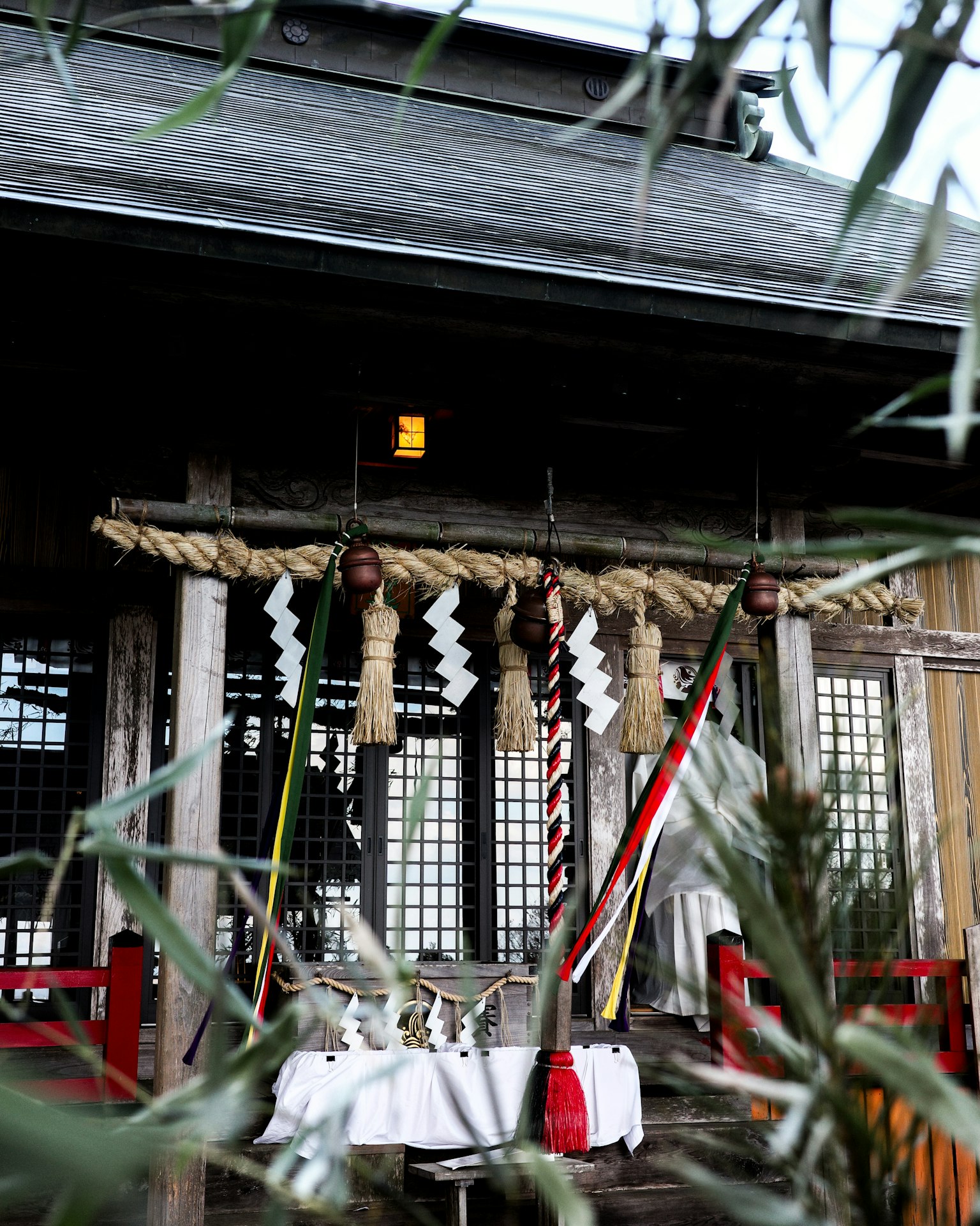 Immagine di un ingresso di un santuario tradizionale con colonne rosse e shimenawa decorativo