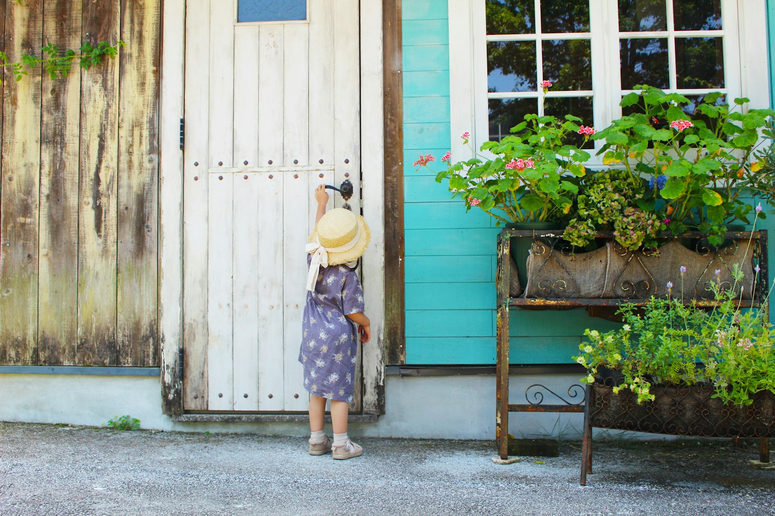 Child knocking on door of a house with blue wall