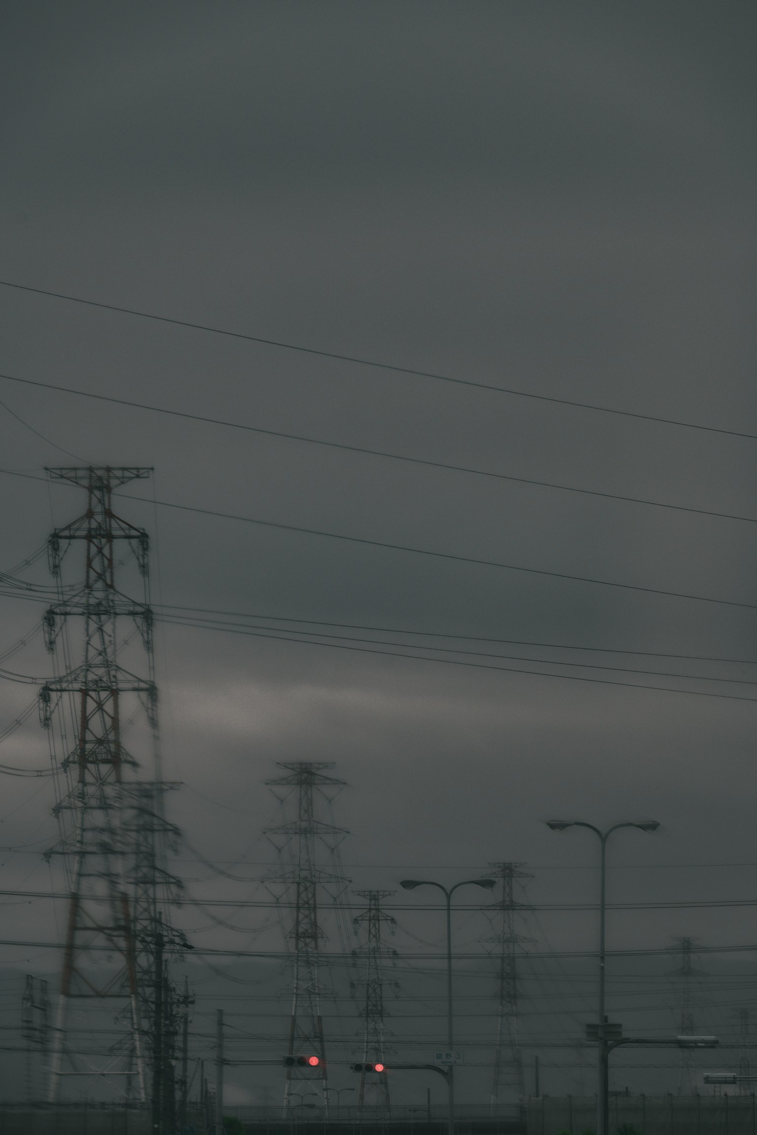 Power lines and poles under a dark, cloudy sky
