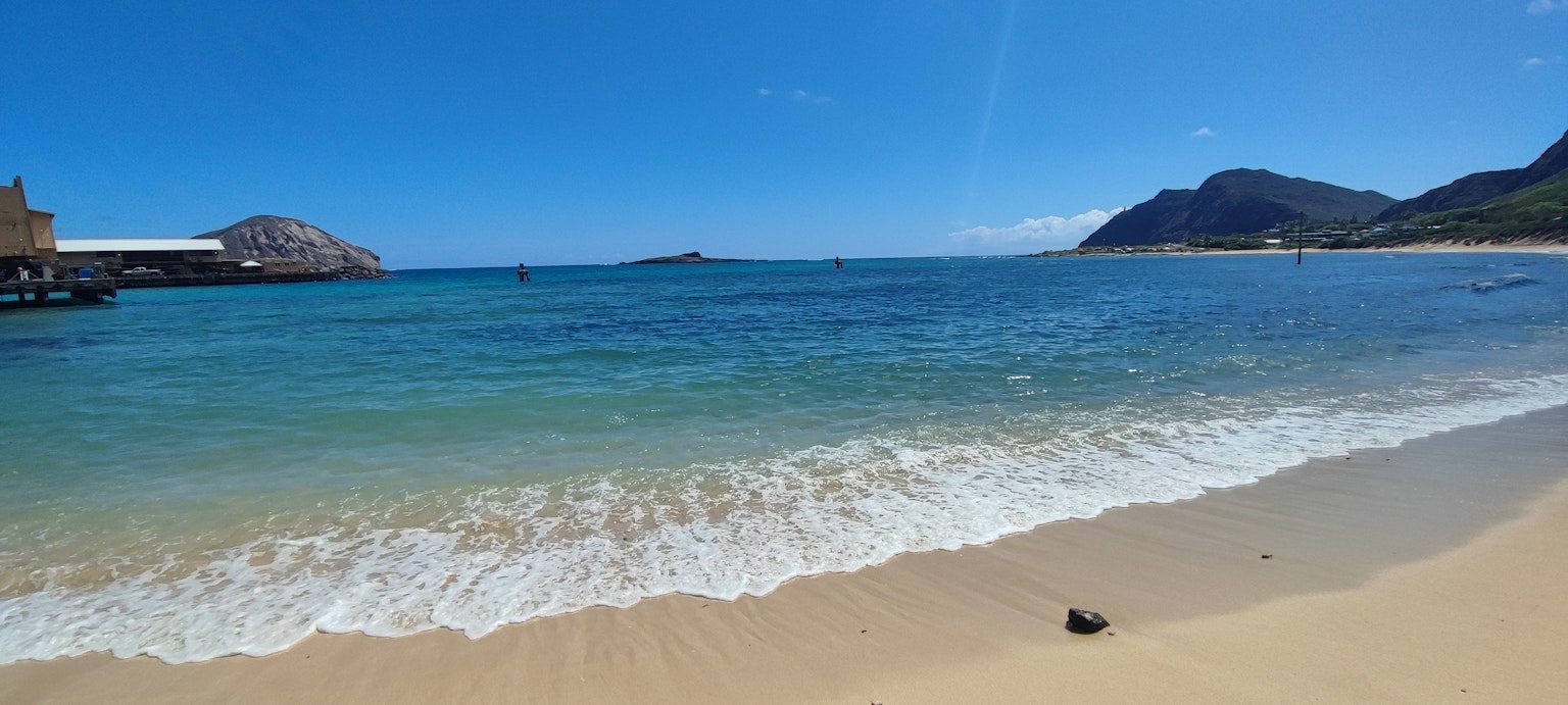 美麗的藍色海洋和白色沙灘的景觀，附近有山和碼頭
