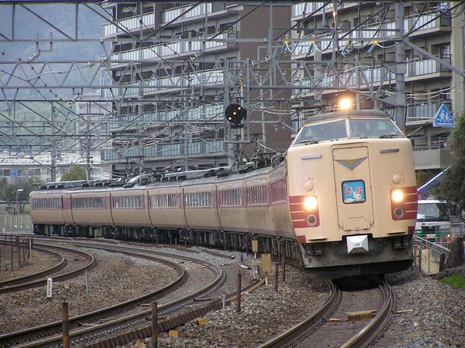รถไฟญี่ปุ่นที่เคลื่อนที่ตามรางโค้งพร้อมอาคารใกล้เคียง