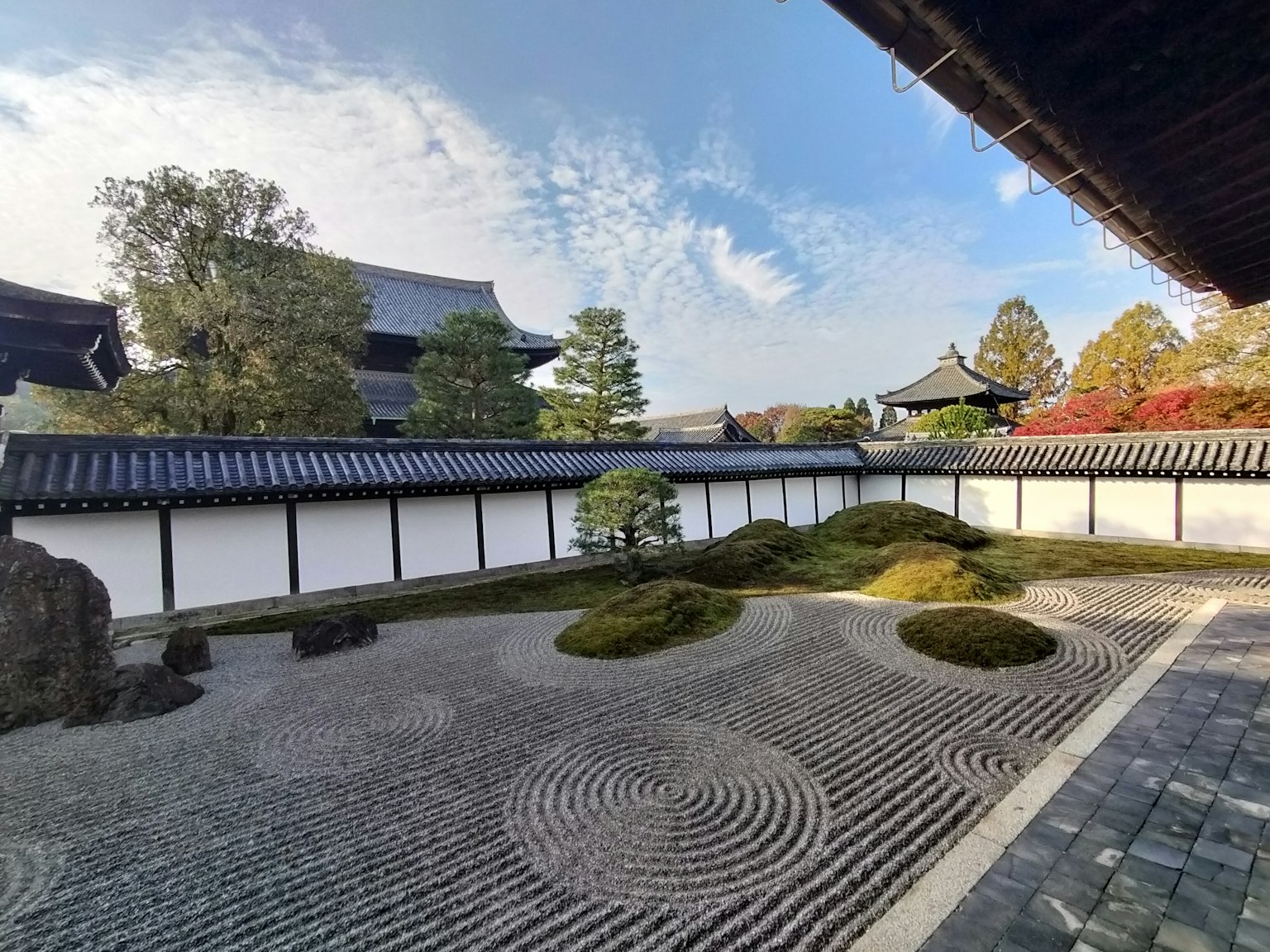 Vista di un bel giardino giapponese con sentieri di pietra e cumuli coperti di muschio accanto a edifici tradizionali
