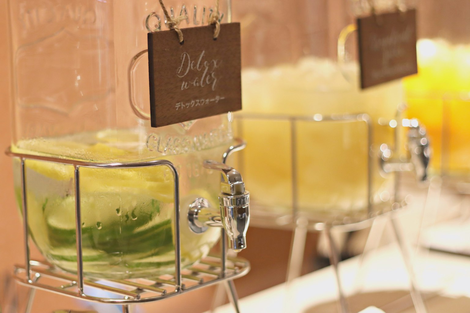 Une scène avec des distributeurs en verre remplis de boissons aromatisées avec du concombre et du citron