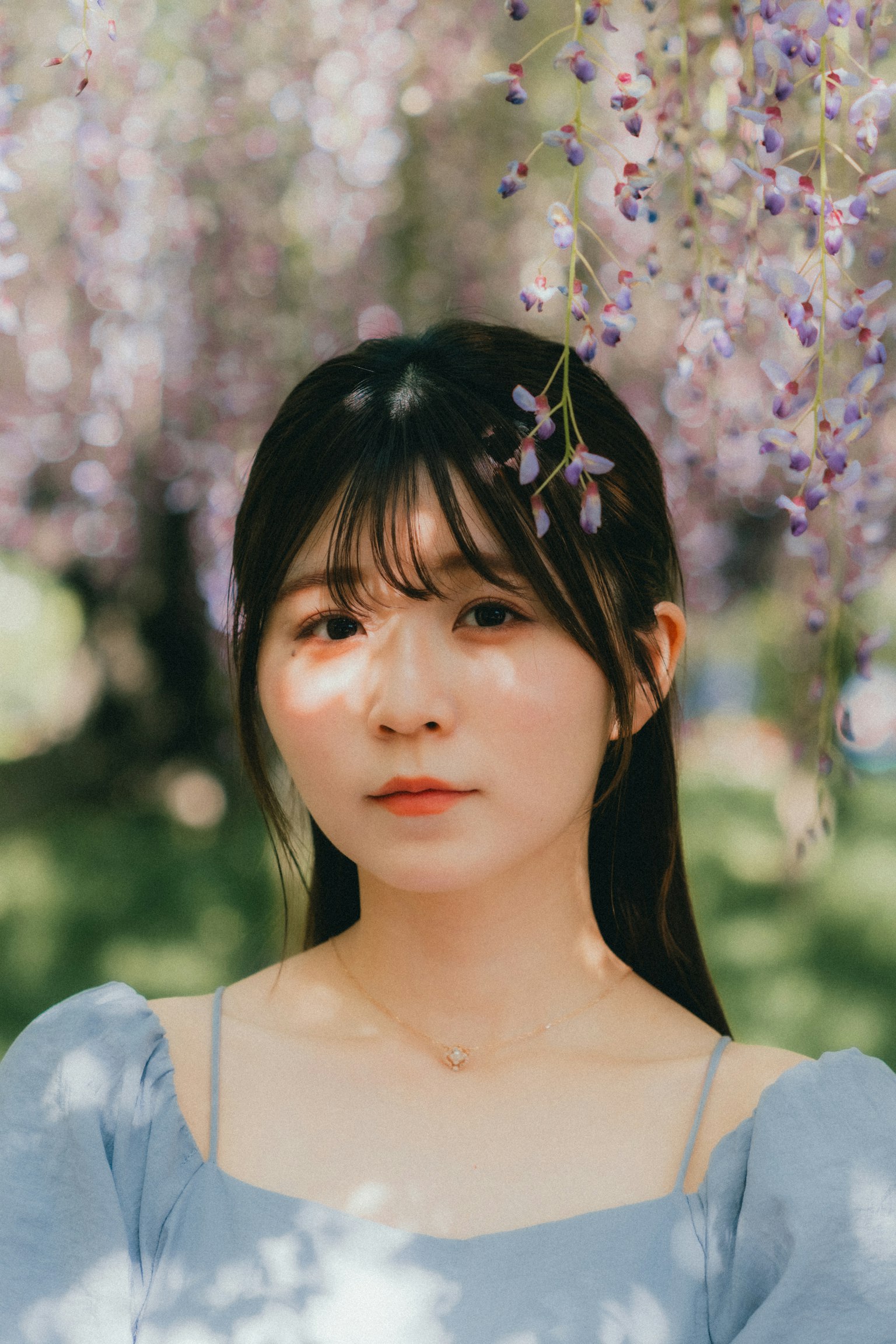 Ritratto di una donna che sorride sotto un albero con fiori viola