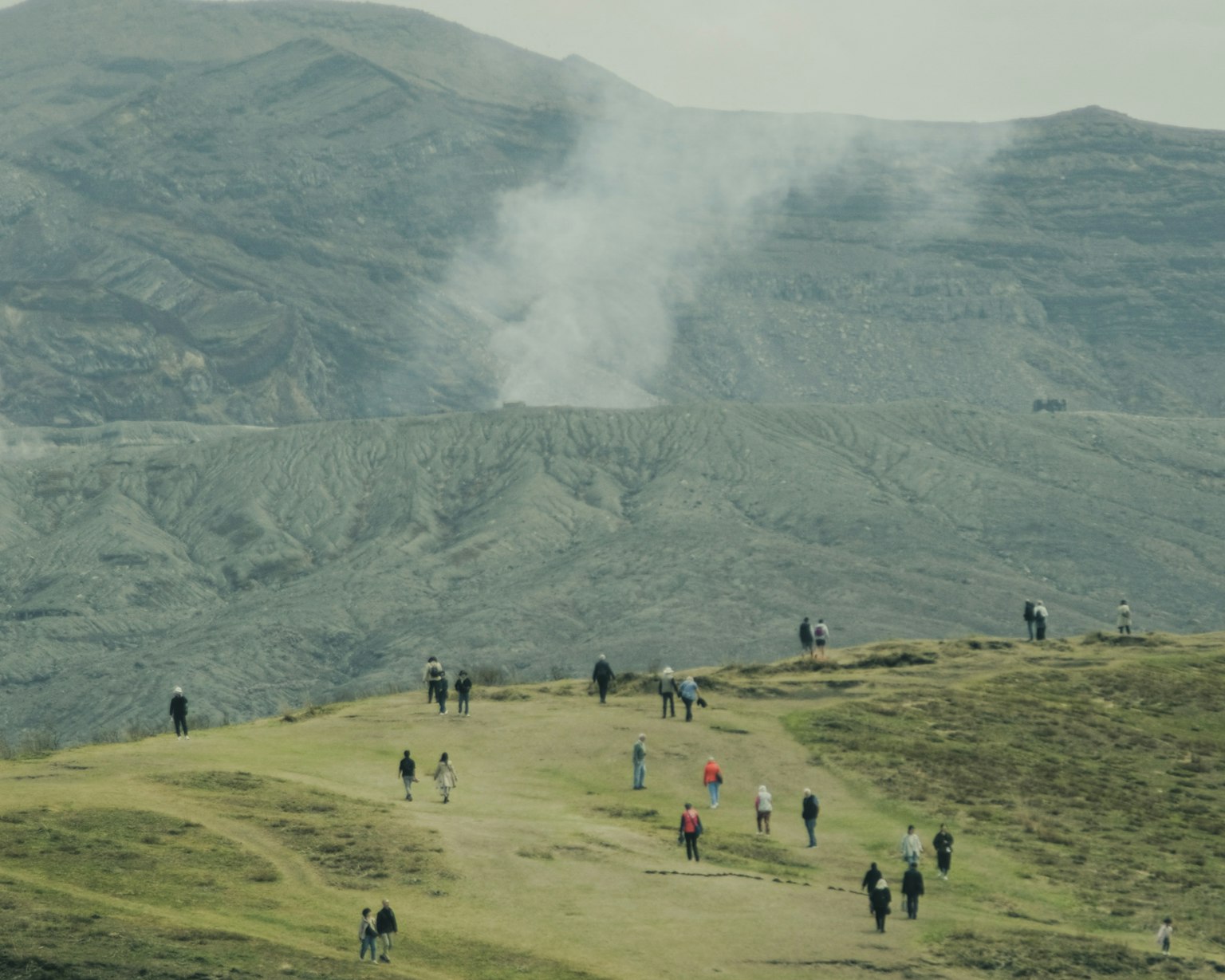 遊客在山丘上行走，背景是山脈和煙霧