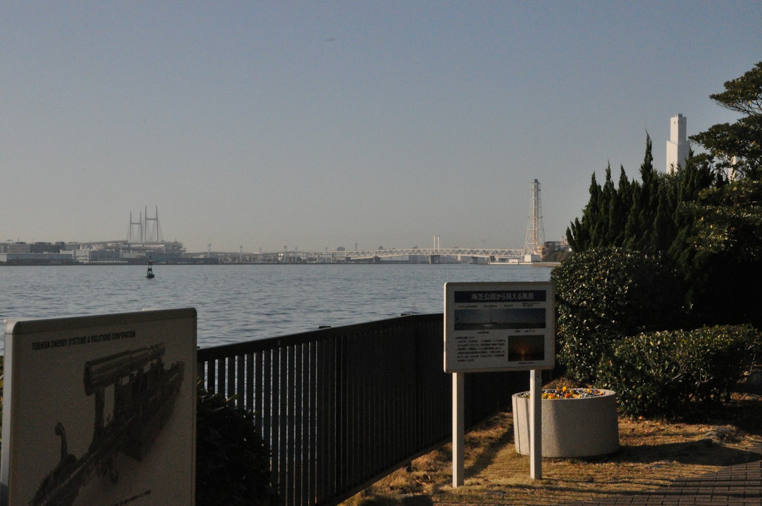 Walkway by the sea with industrial landscape and information signs