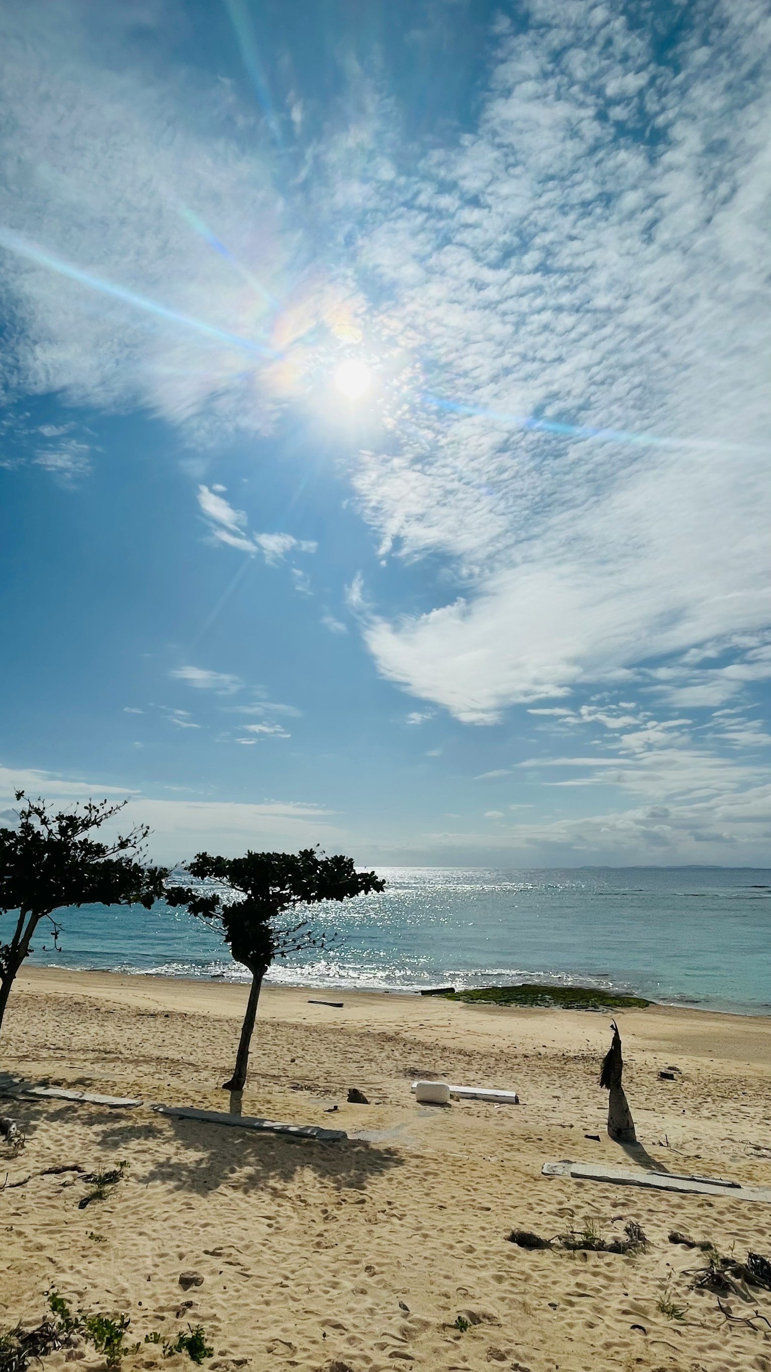 ทิวทัศน์ชายหาดที่มีท้องฟ้าสีฟ้าและเมฆสีขาว คลื่นอ่อนๆ ซัดเข้าหาฝั่ง
