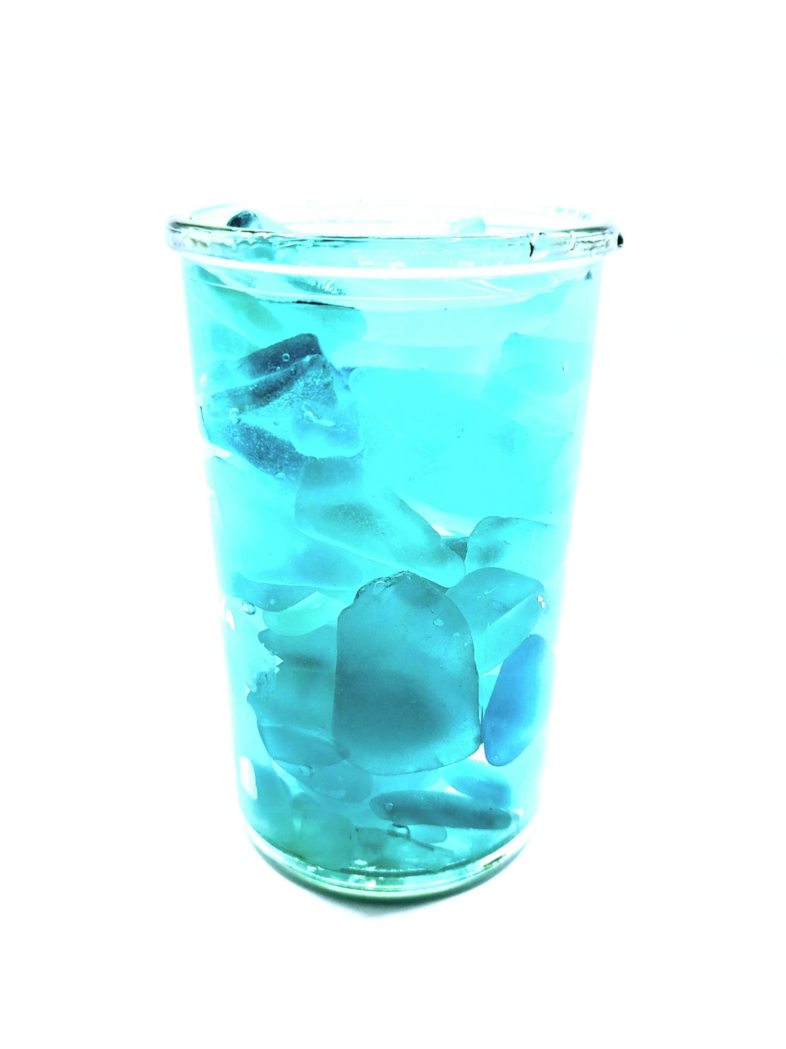 Un vaso lleno de una bebida azul y cubitos de hielo