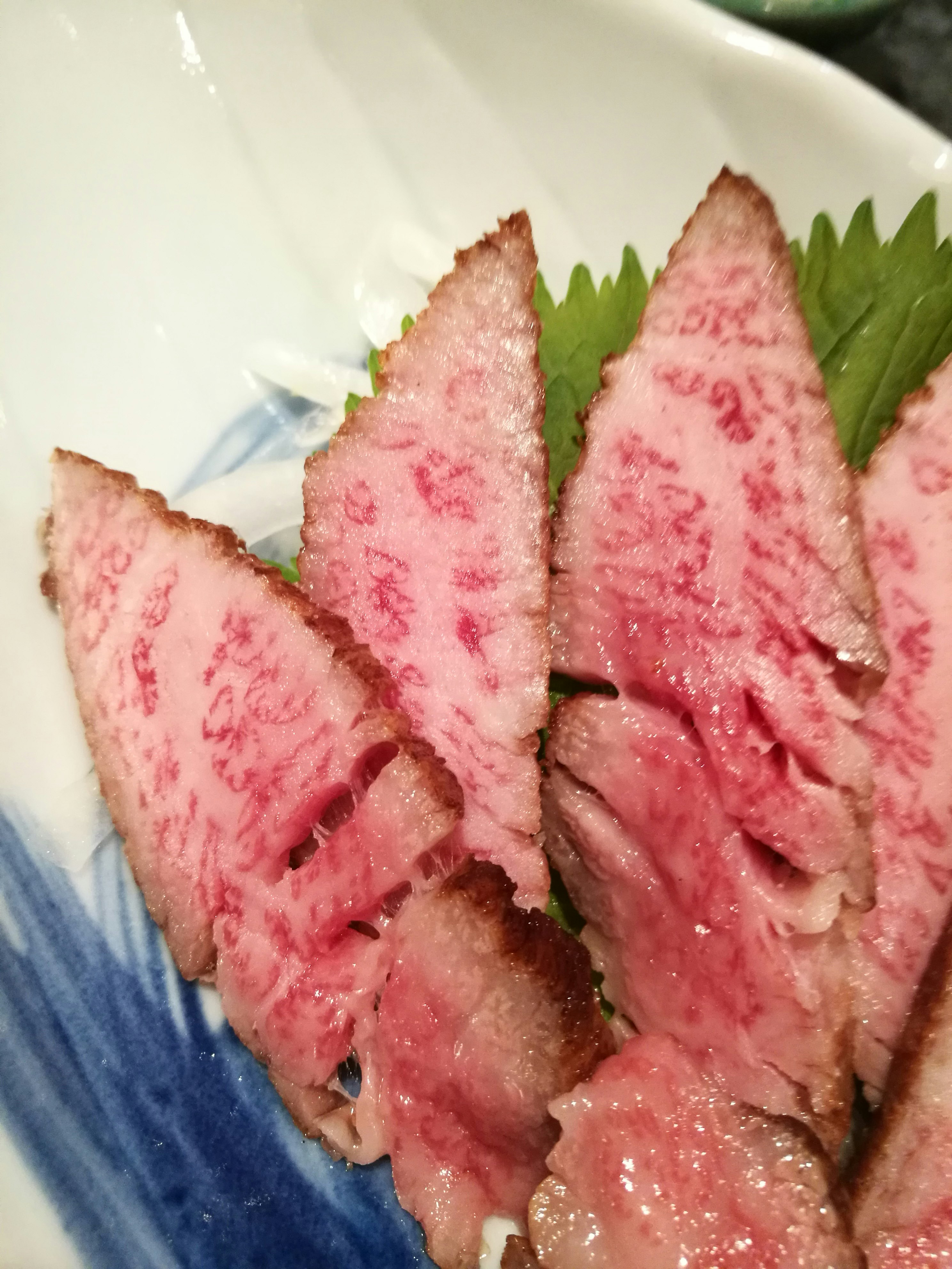 白盤上的生魚片配紫蘇葉