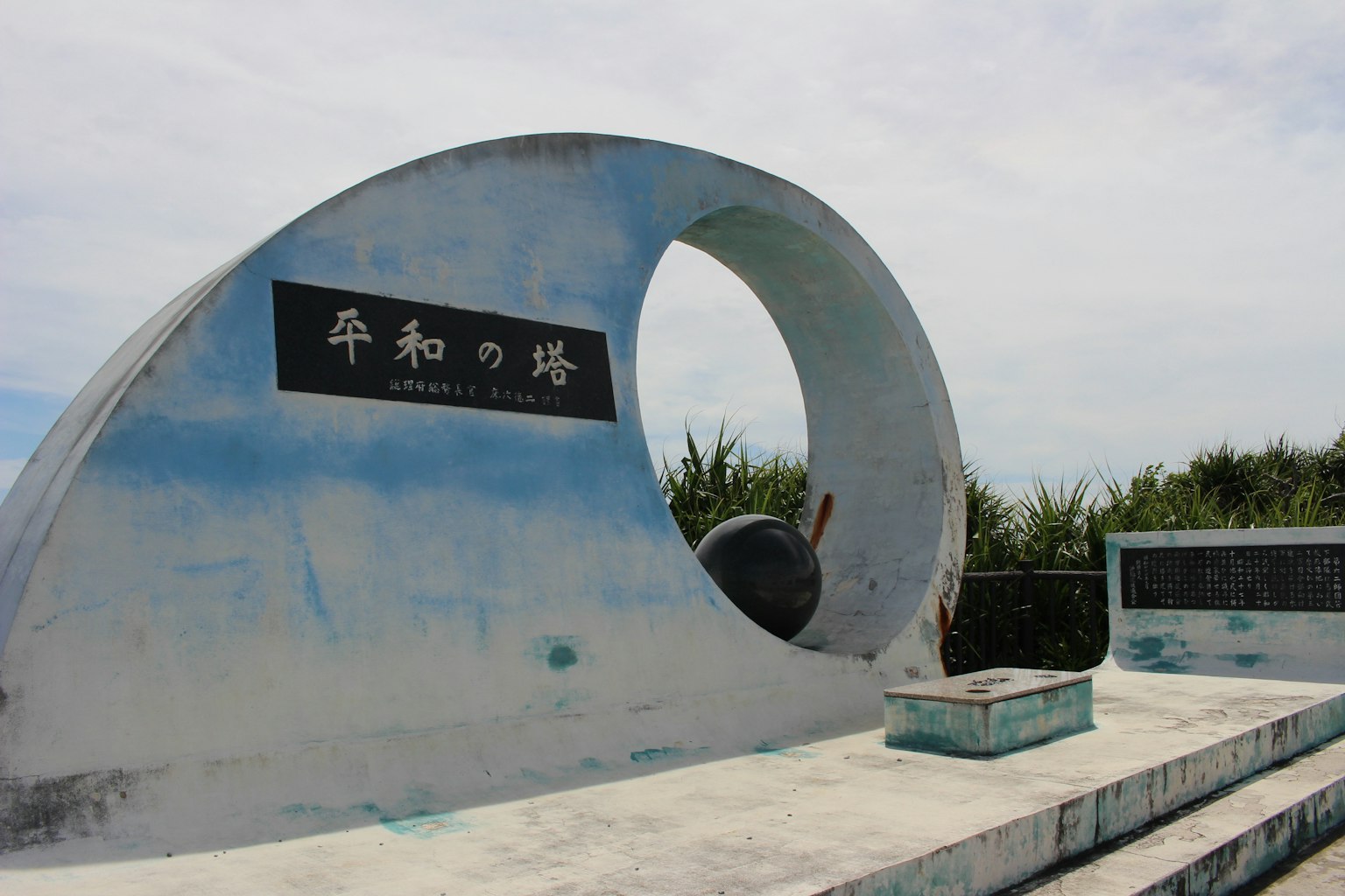 Un monument en forme de vague bleue avec l'inscription Monument de la paix