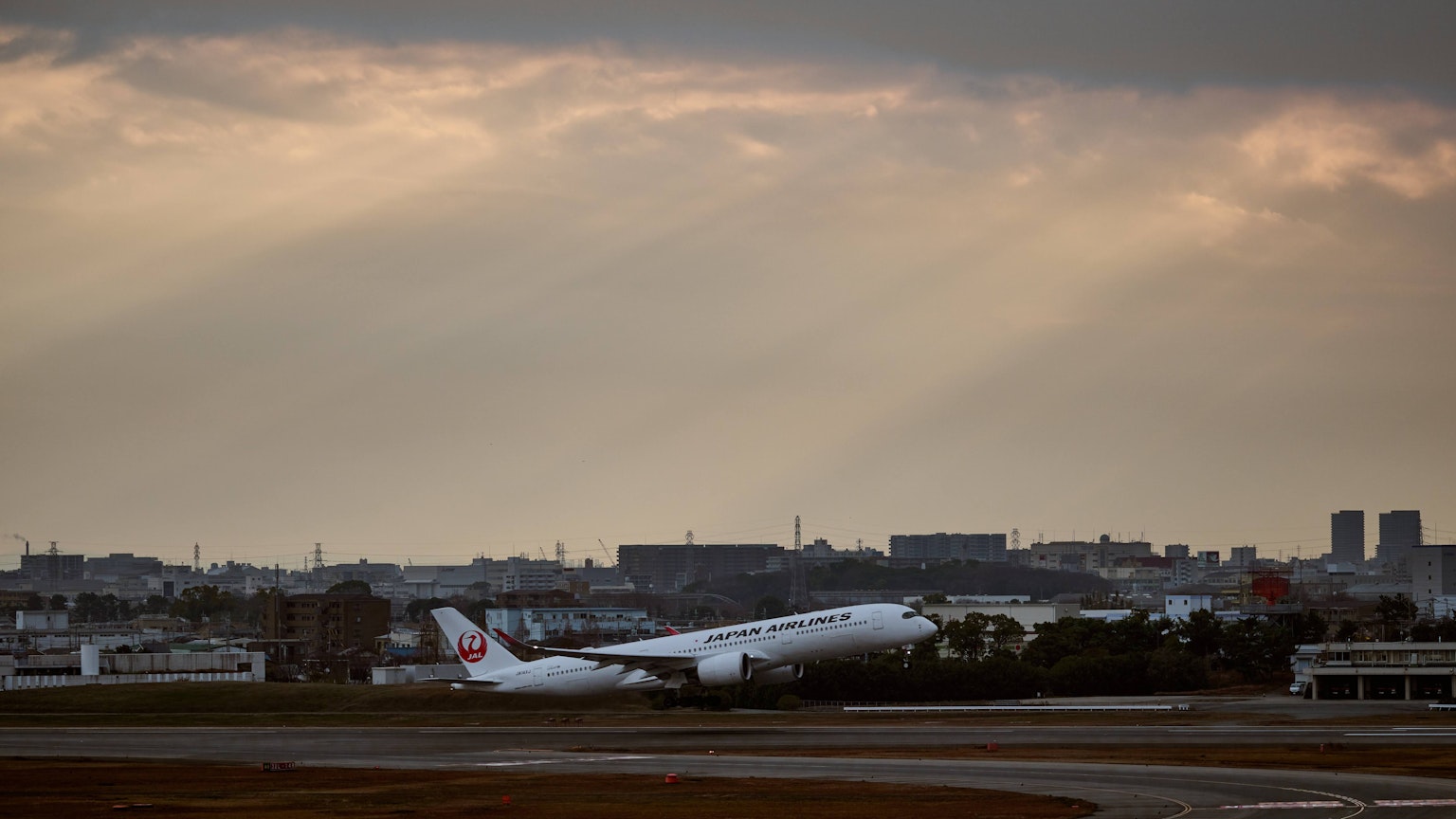Aereo in decollo al tramonto con paesaggio urbano sullo sfondo