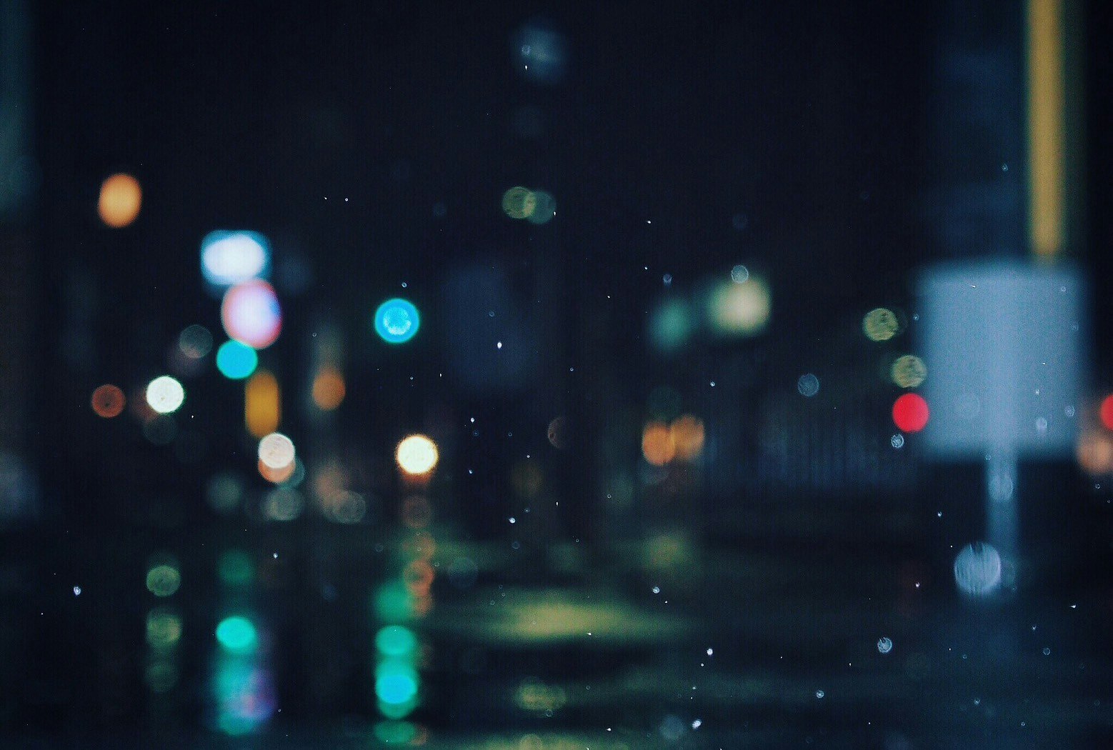 夜の雨上がりの街で光がにじむ路上の風景