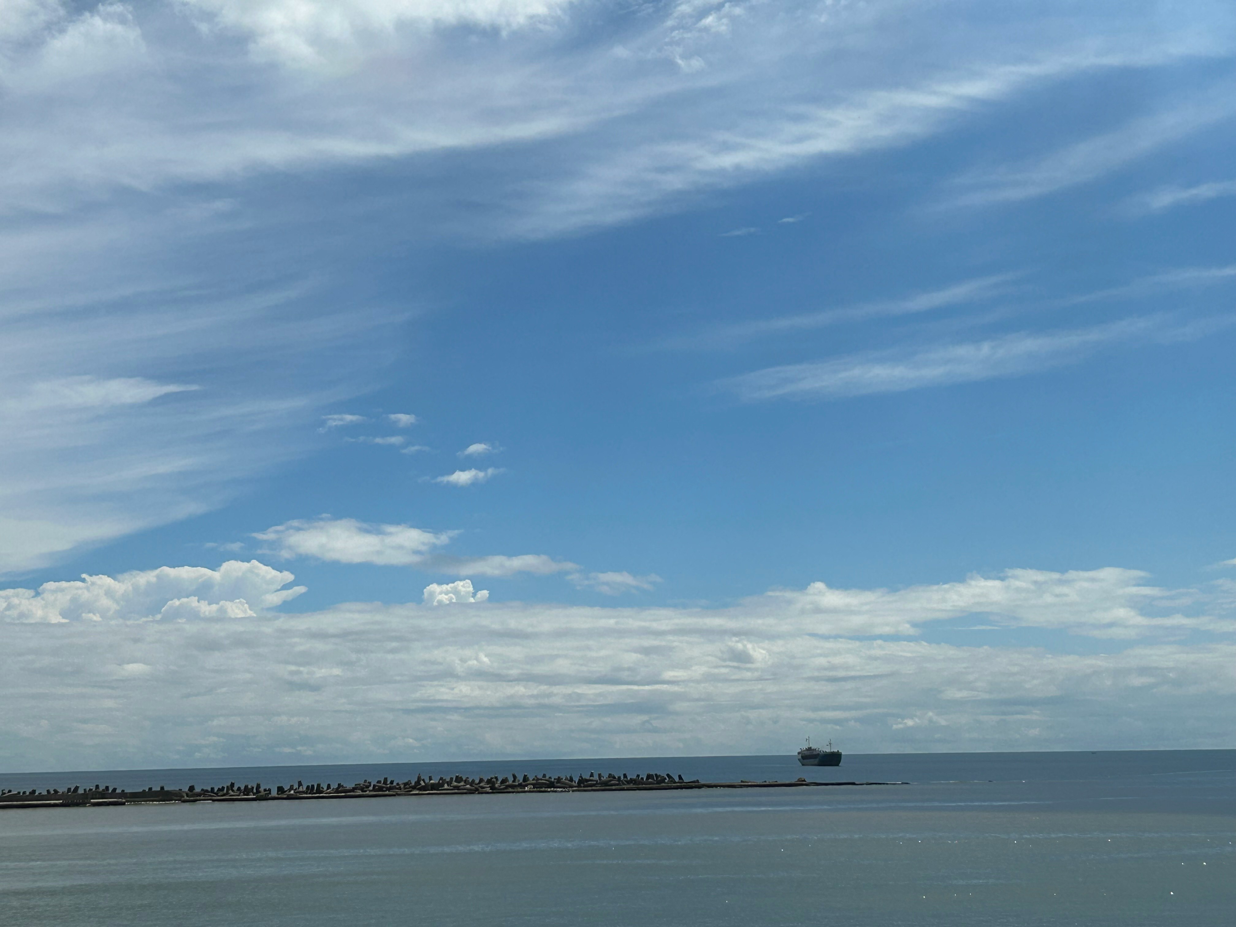水平線に浮かぶ小さな船と広がる海の風景