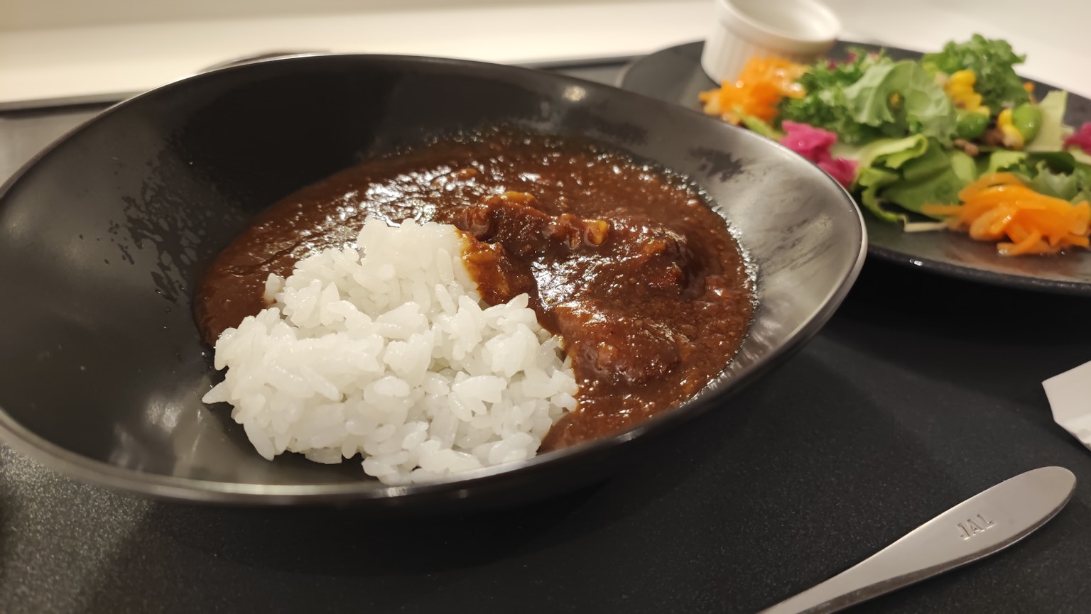 ข้าวแกงกะหรี่ในชามสีดำพร้อมสลัดข้างเคียง