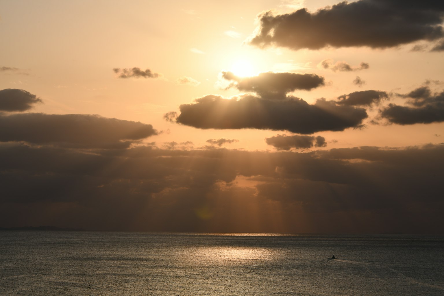 Tramonto sull'oceano con nuvole e raggi di luce
