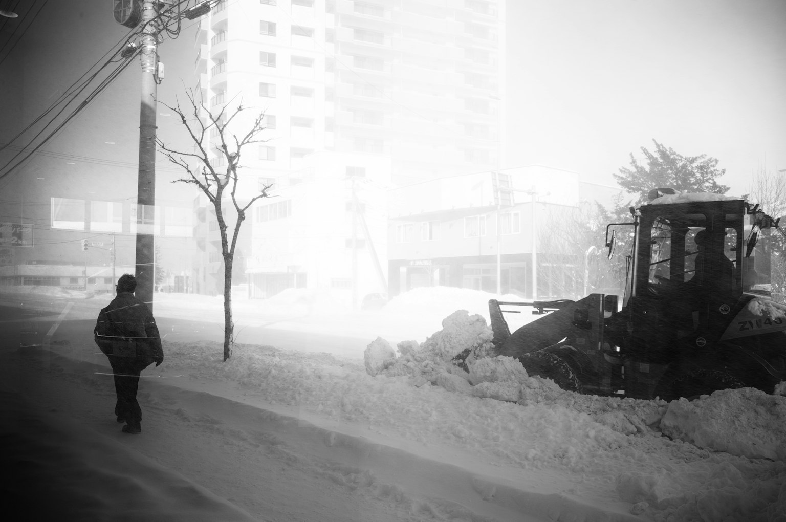 Une personne marchant sur une rue enneigée à côté d'un chasse-neige