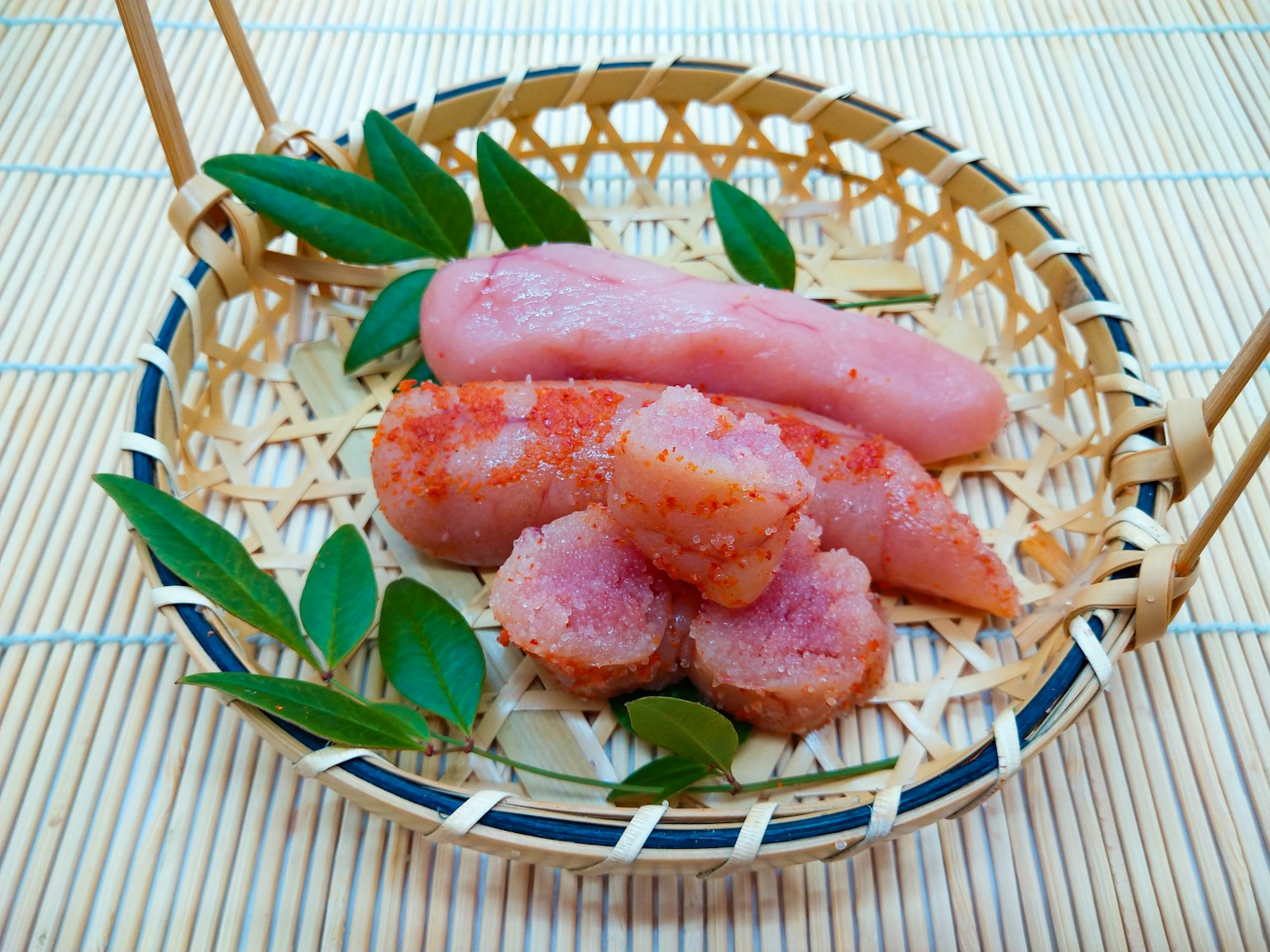 Huevas de pescado rosa y hojas dispuestas en una canasta de bambú