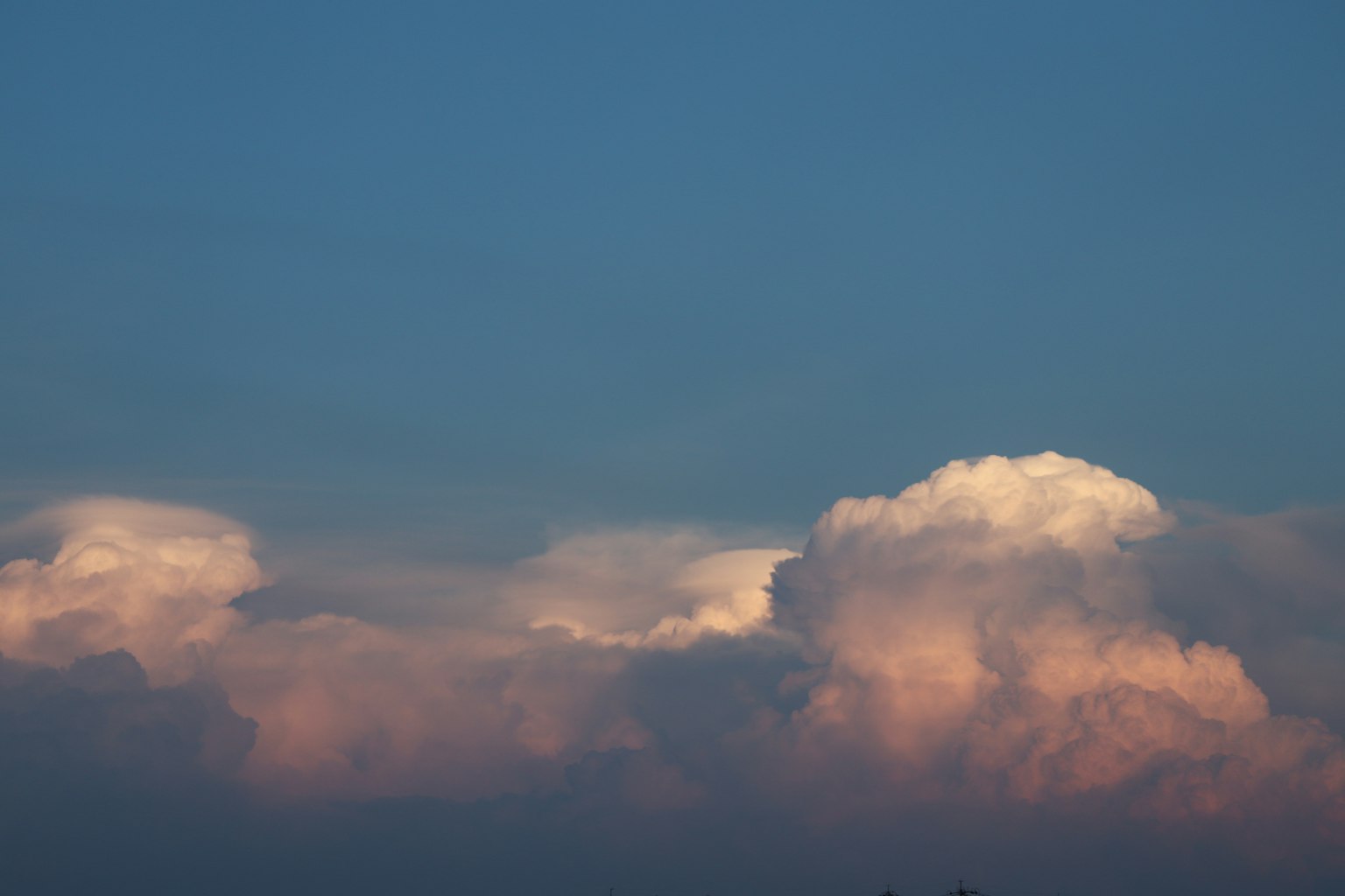 Nuages blancs illuminés par une lumière orange sur un ciel bleu