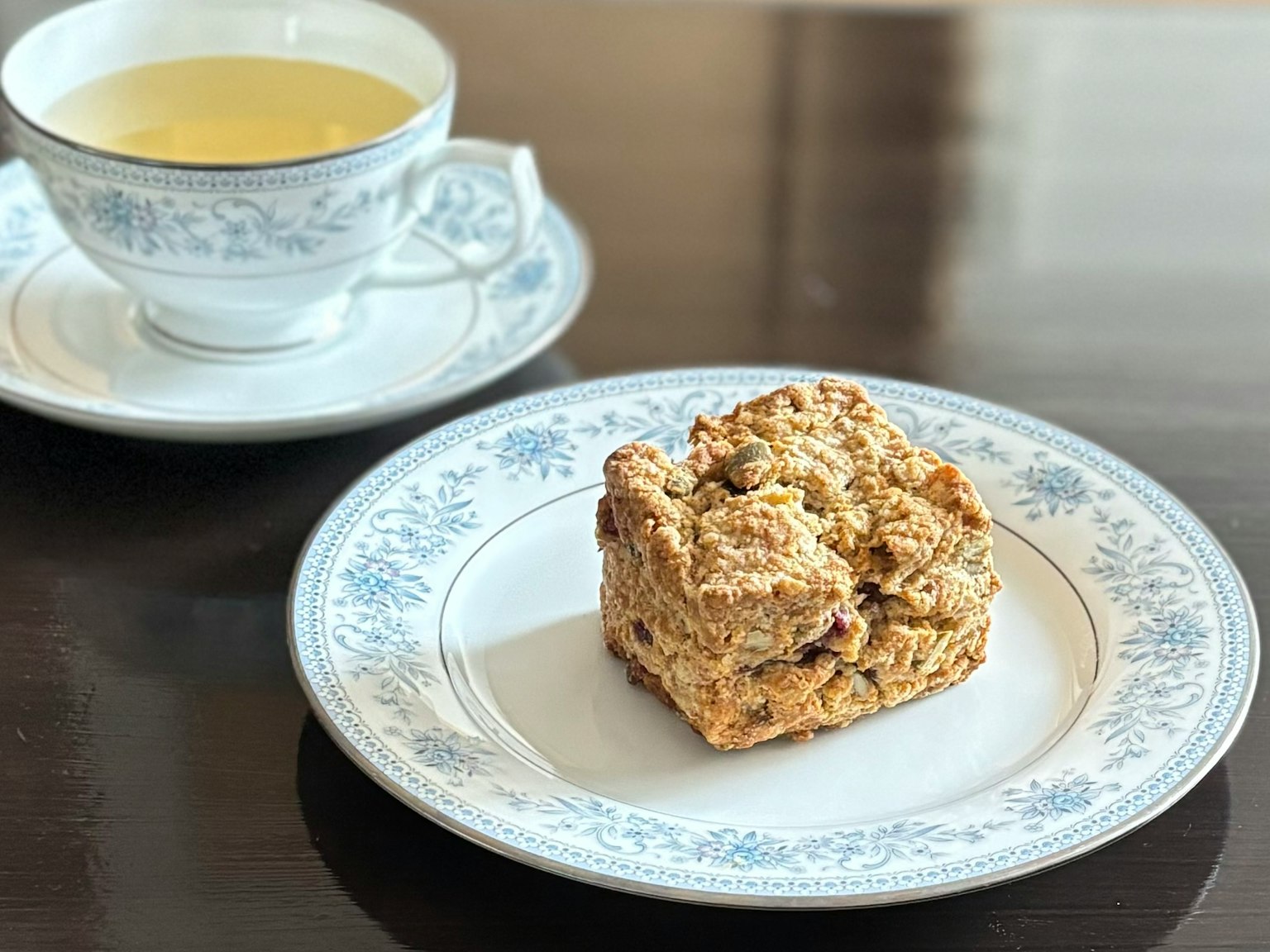 Dolce su un piatto floreale blu con una tazza di tè