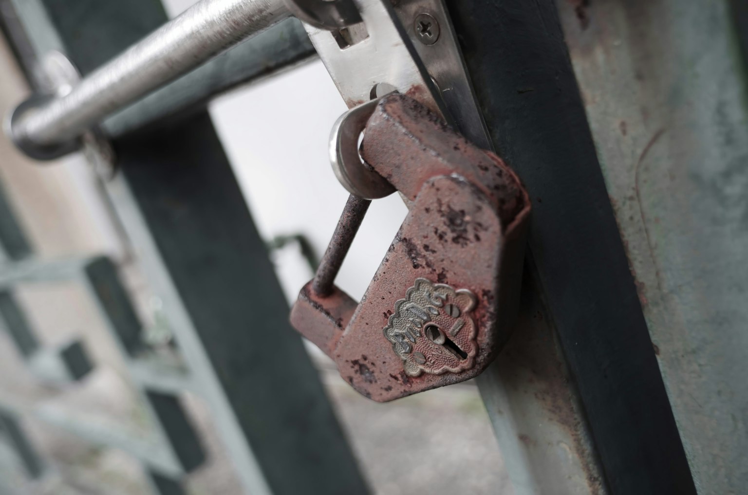 Rusty padlock hanging on a closed gate